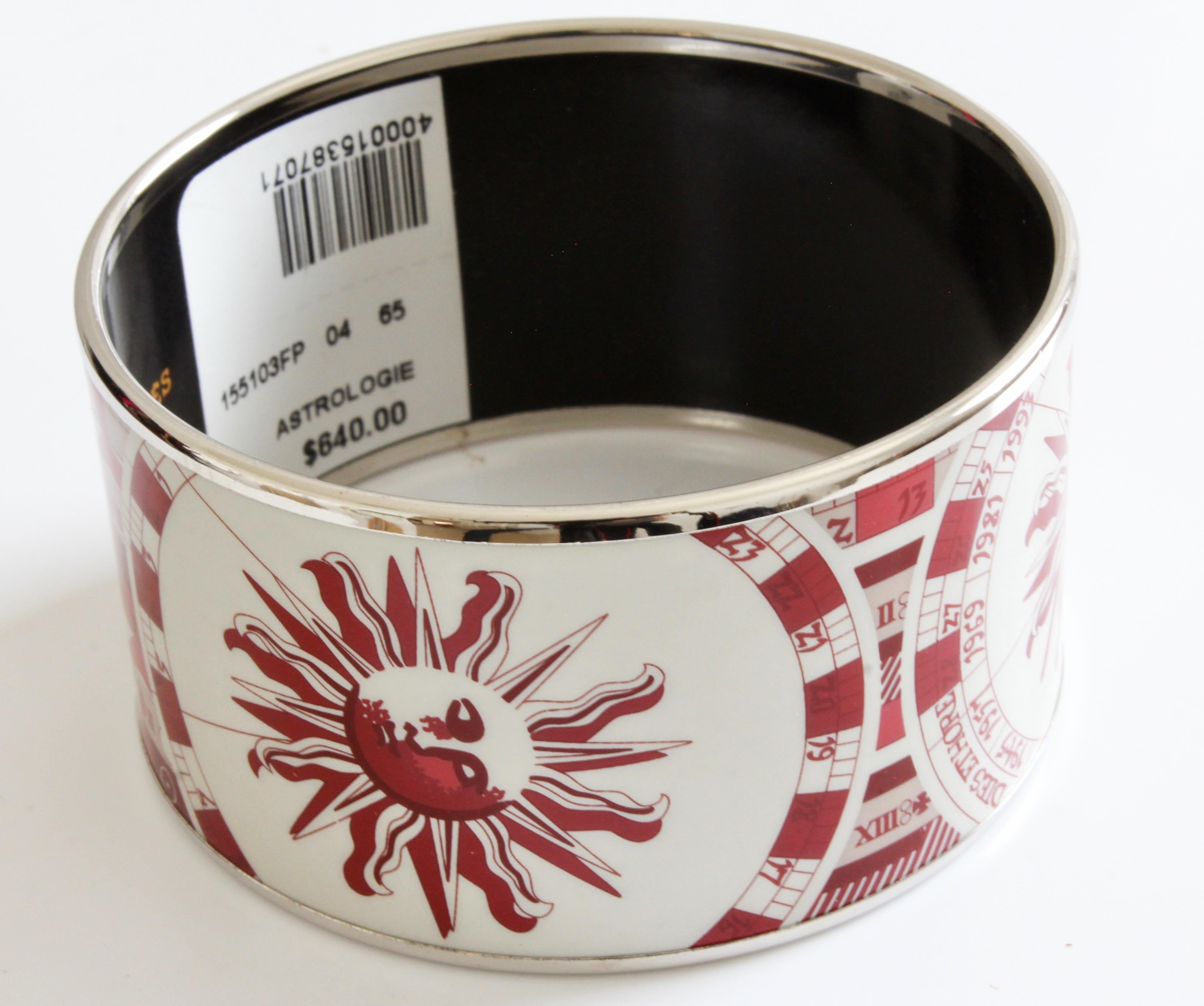 This fabulous and hard to find extra wide printed enamel bracelet was made by Hermes in 2005. Coined ASTROLOGIE, it features a large sun with zodiac calendar in red and white with silver trim. No longer in production and so hard to find, especially