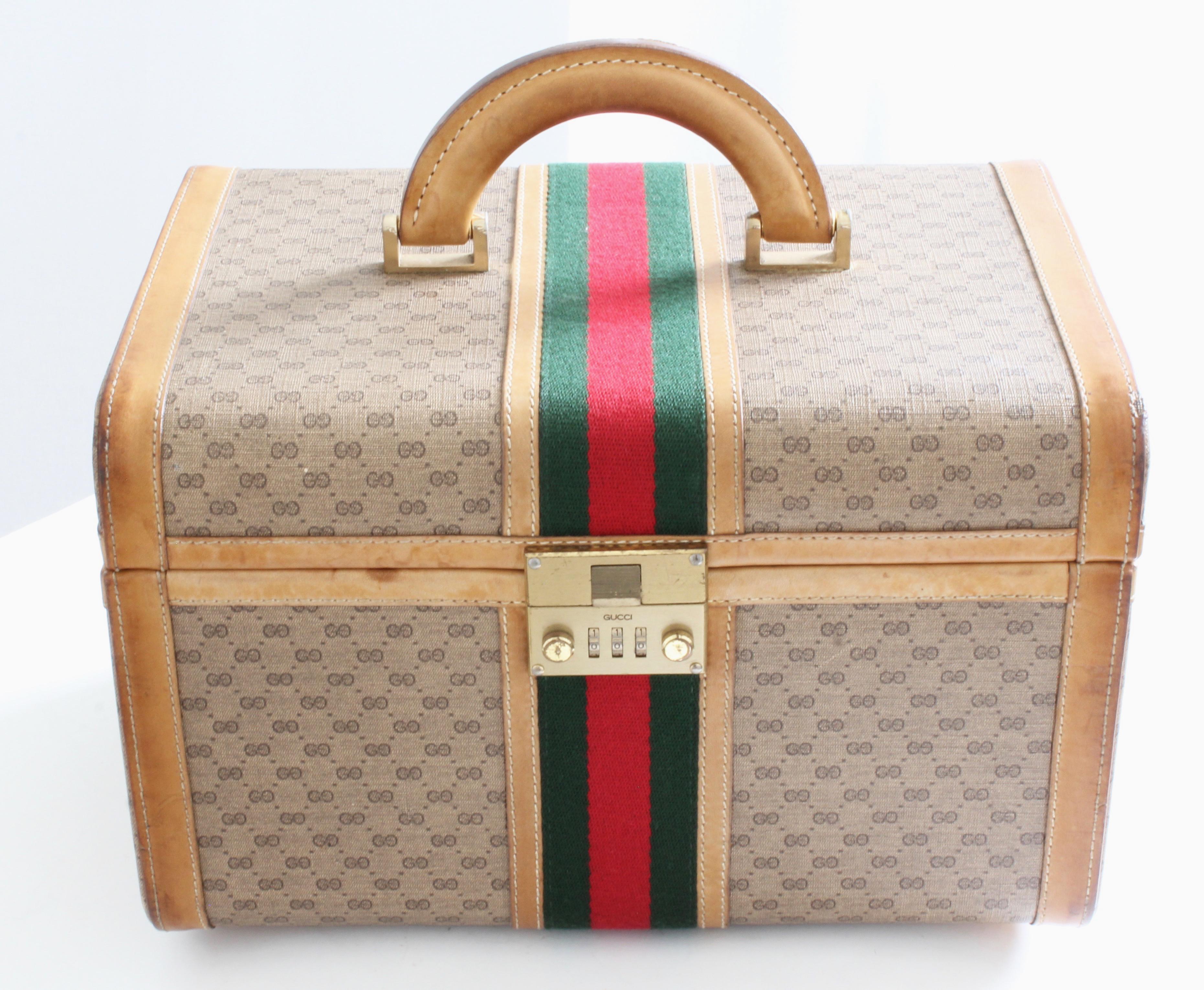This fabulous vintage train case was made by Gucci, most likely in the early 1980s.  Made from their small GG logo canvas, it's trimmed in light saddle leather and features Gucci's iconic webbing at the center.  Fastens with a combination lock (set