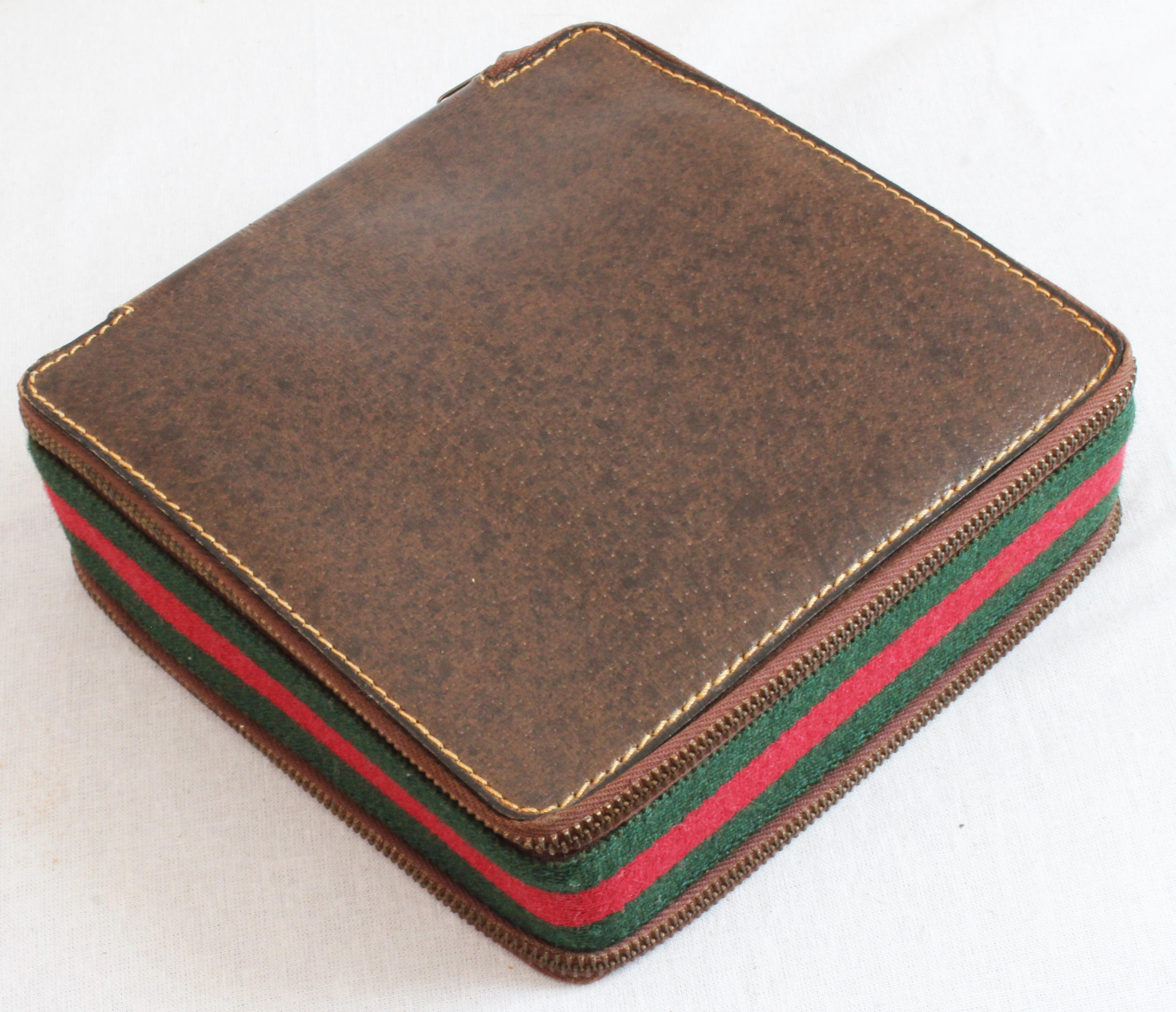 This travel game set was made by Gucci in the 1970s as a special order.  Made from brown leather, the case features their signature webbing at the center and zippers on each side: one side holds two decks of playing cards and 7 dice, and the other