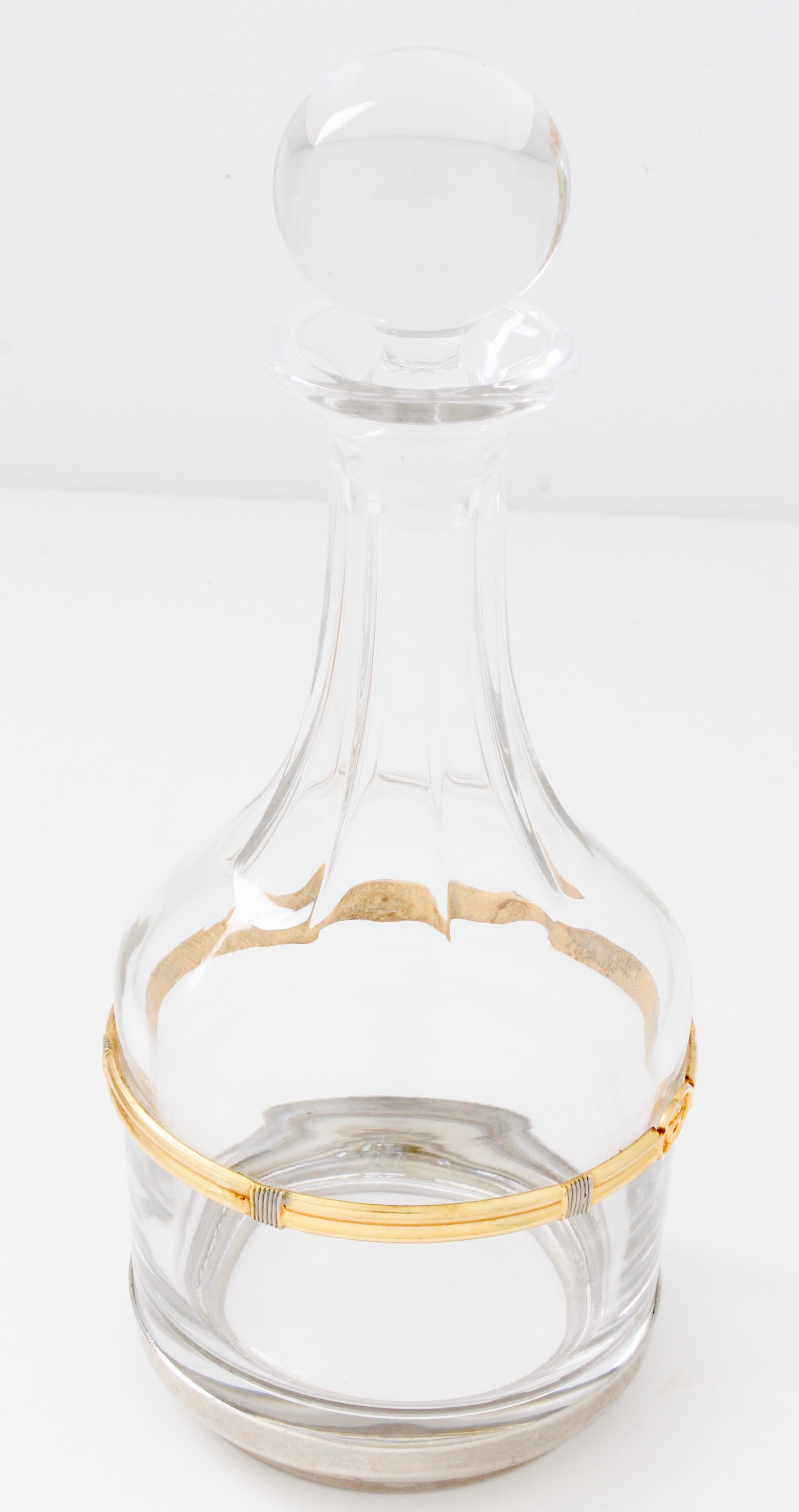 Entertain in high style with this rare crystal wine decanter from Gucci, likely made in the 1970s.  It comes with its round crystal stopper and features a gold and silver metal rope motif band with GG logo at the center, and a silver metal base. 