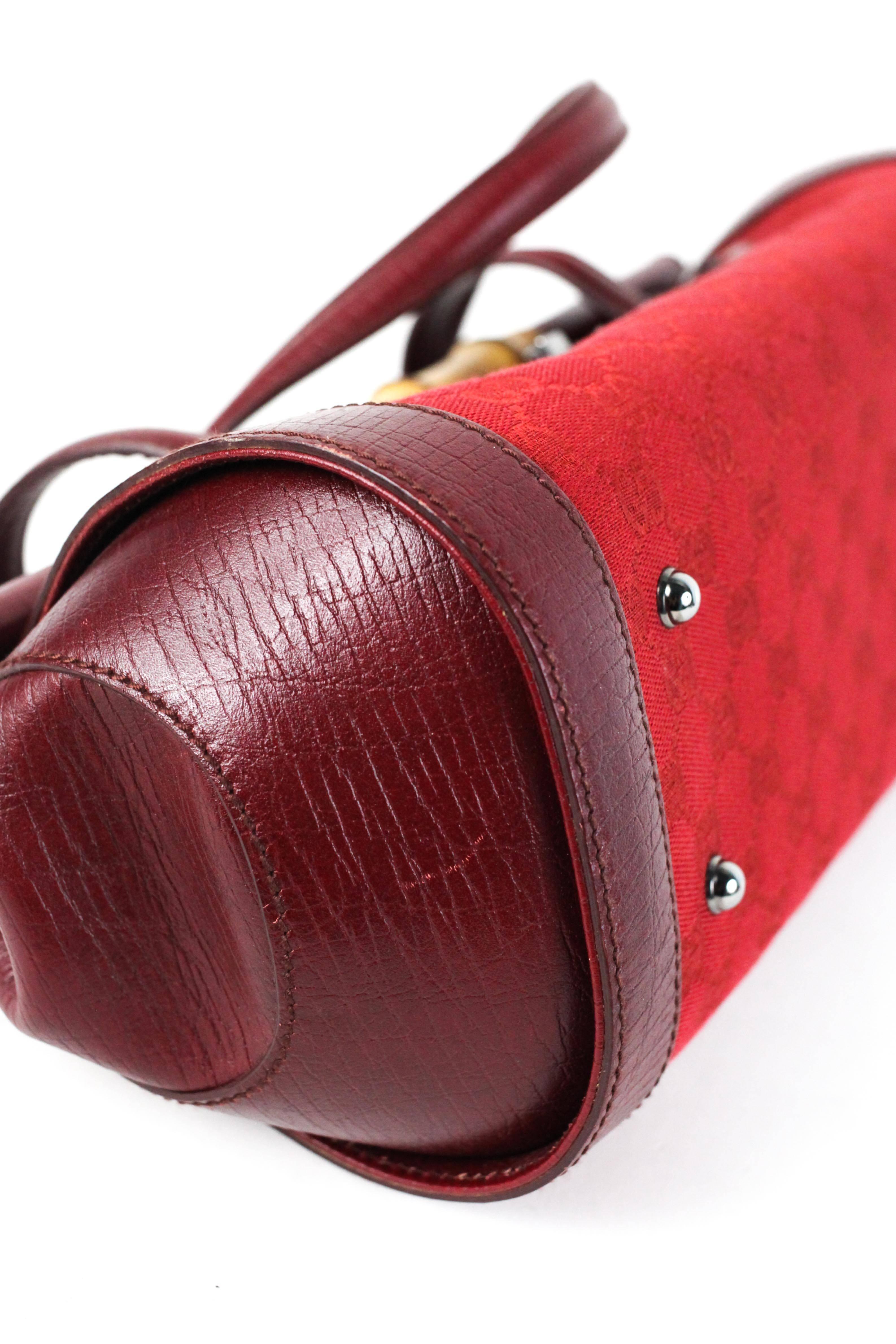 Offered is a unique piece from Gucci.  Brilliant red leather barrel style with red logo canvas  trim down the front.  Bamboo trim across the handle with a gunmetal closure. Framed rolled leather across the flap with two flat leather handles. Studded