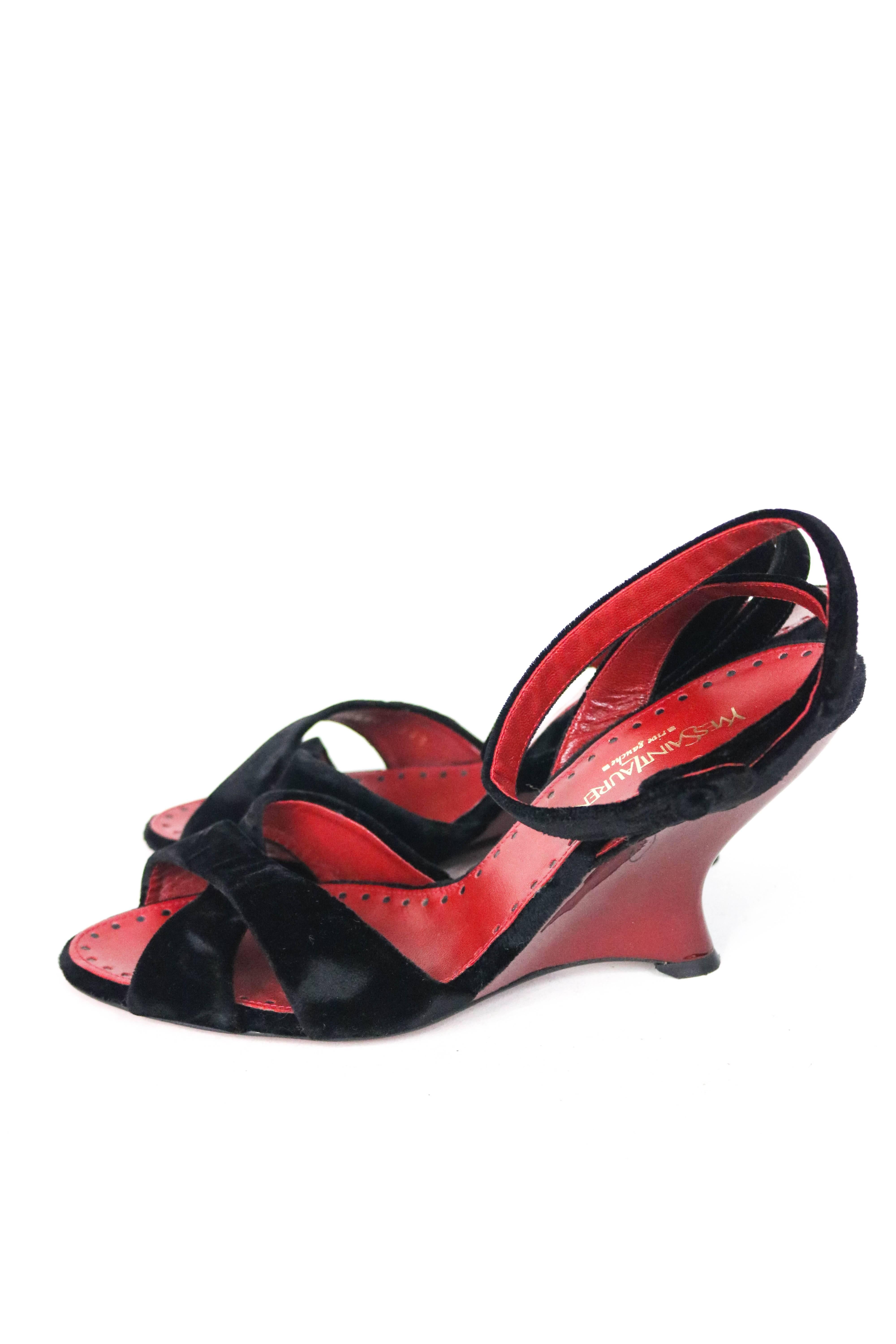 Offered is a gently pre-owned pair of Yves Saint Laurent black velvet evening shoes with a beautiful glossy sculptured wedge heel.  A twist across the front and a delicate ankle strap compose the upper, and the cole is classic red.  Worn gently ,