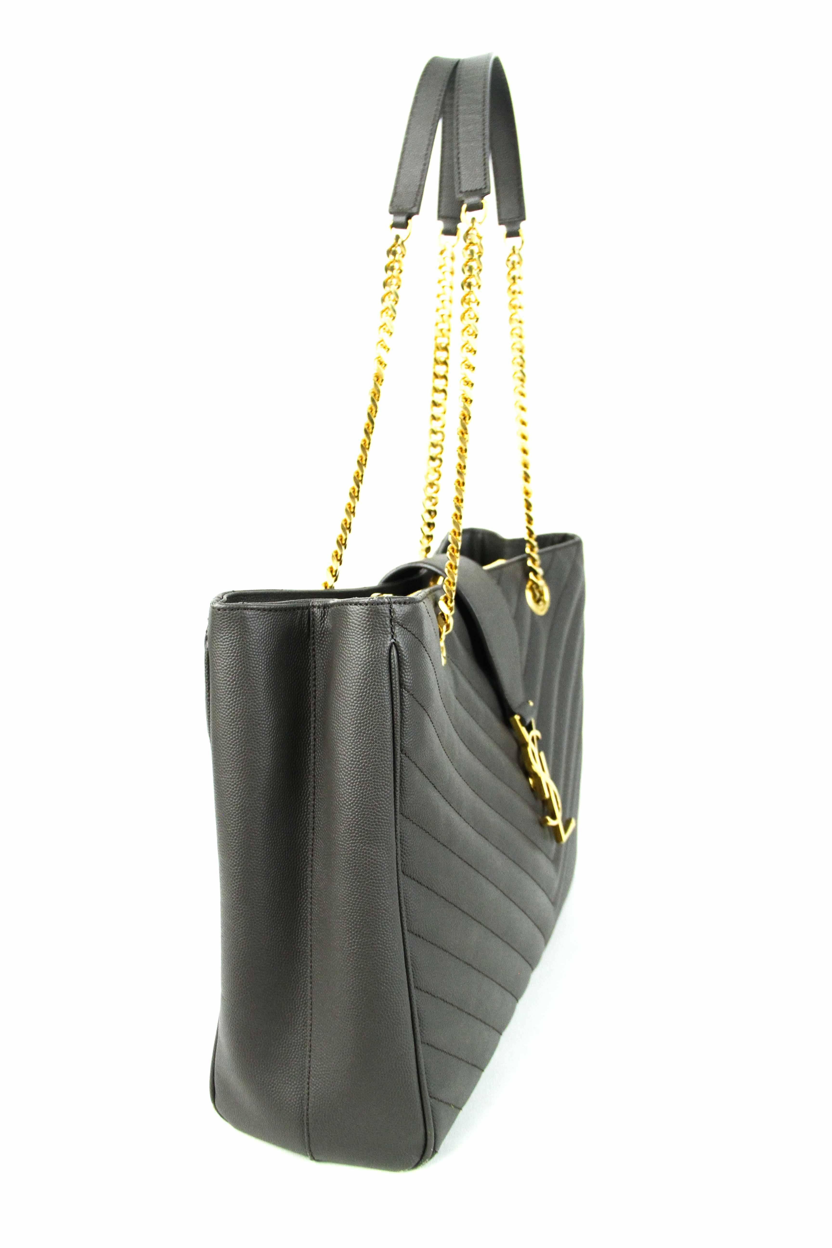 Offered is an authentic near new , never worn, YSL large shopping tote in a luxurious gray color. Tonal topstiching creates a chevron pattern, accented by gold-tone YSL logo medallion.  Curb chain handles with leather insets.  Zip  center