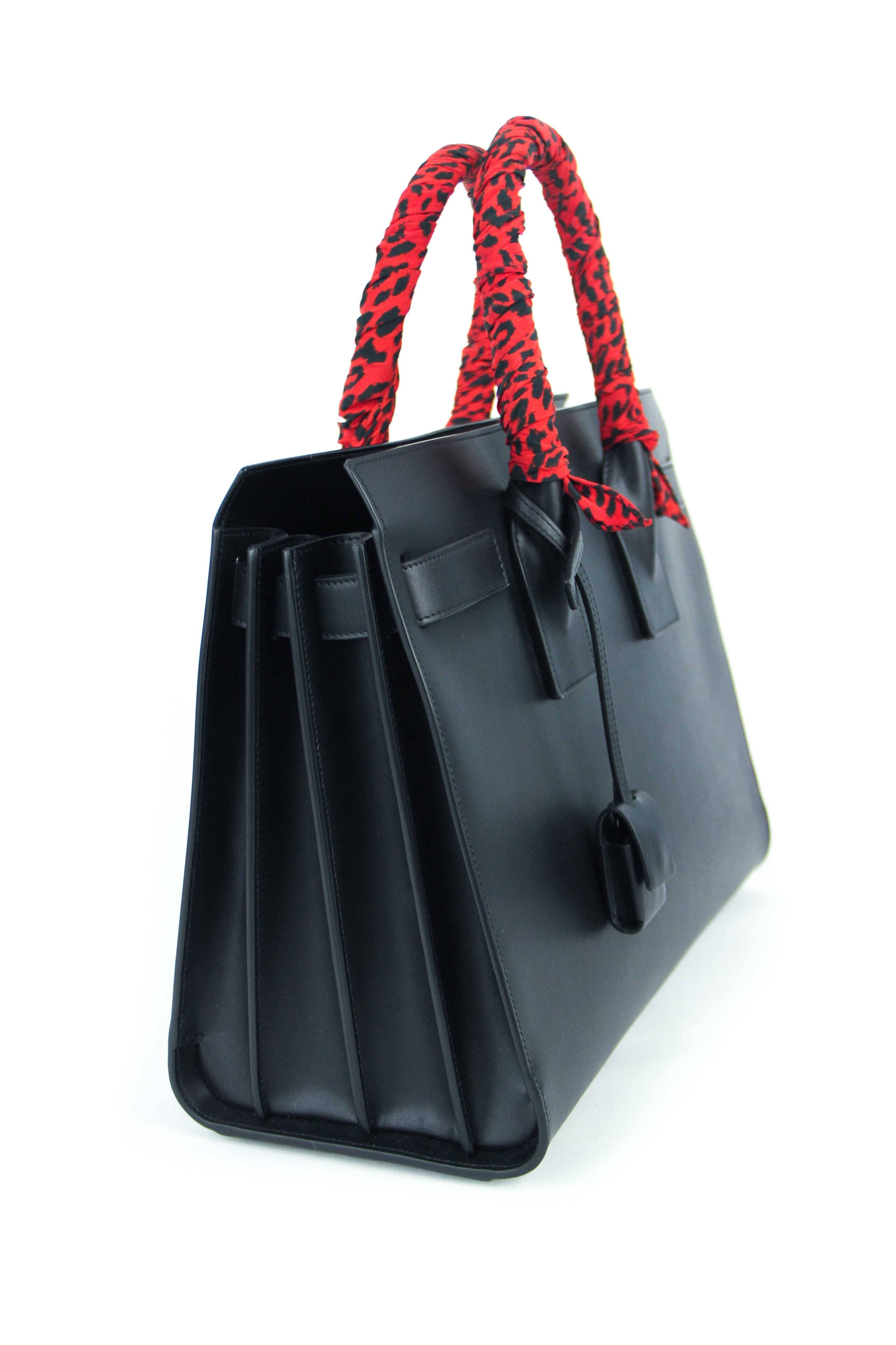 Offered is a pre-owned never used small black Sac De Jour from Saint Laurent.
Babycat printed scarf wrapped handles in black and red. Smooth calfskin with black-tone hardware.  Comes with original tags and dustbag. Features an adjustable detachable