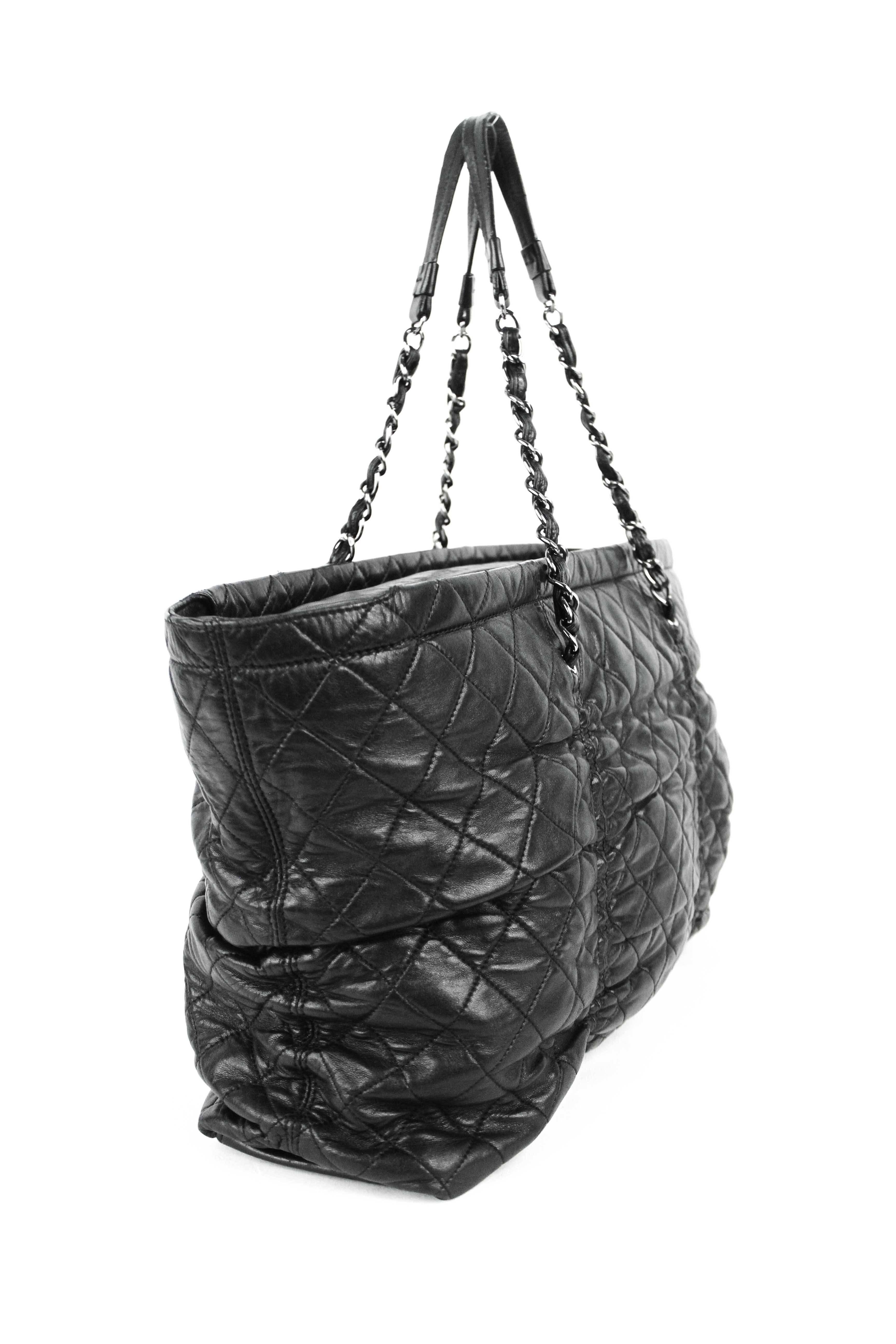 Offered is a pre-owned Chanel quilted lambskin tote with classic chain handles.  Ultra soft black lambskin complimented by silver-tone hardware.  Zip top closure, with a gray textile lining.  Good condition , wear can be seen on bottom leather