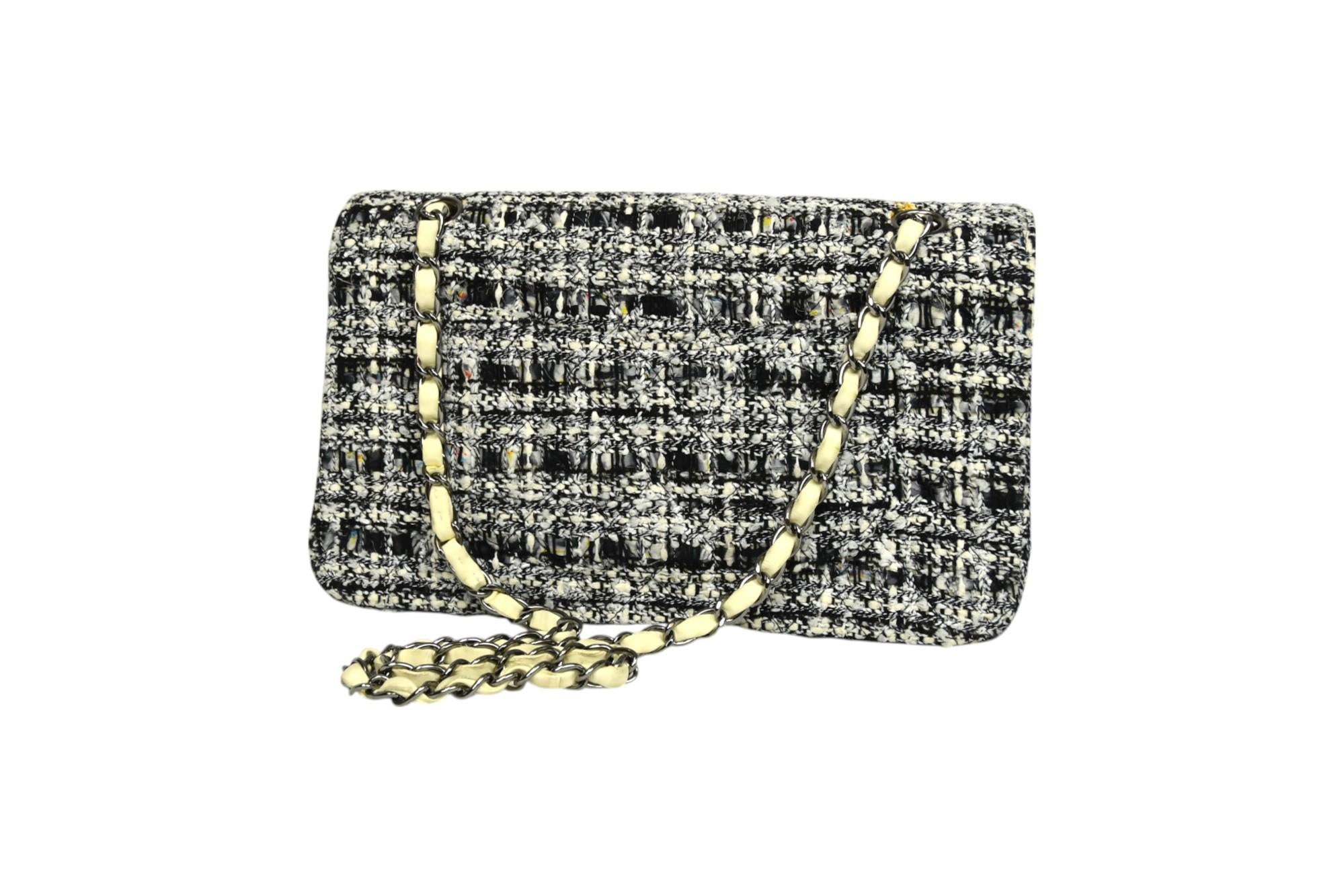 La borsa Chanel Classic Medium Double Flap è una splendida reinterpretazione di un'icona della Maison, realizzata in tweed bianco e nero glitterato per un effetto fresco e dimensionale. Il sottile luccichio intrecciato nel tessuto bouclé aggiunge un