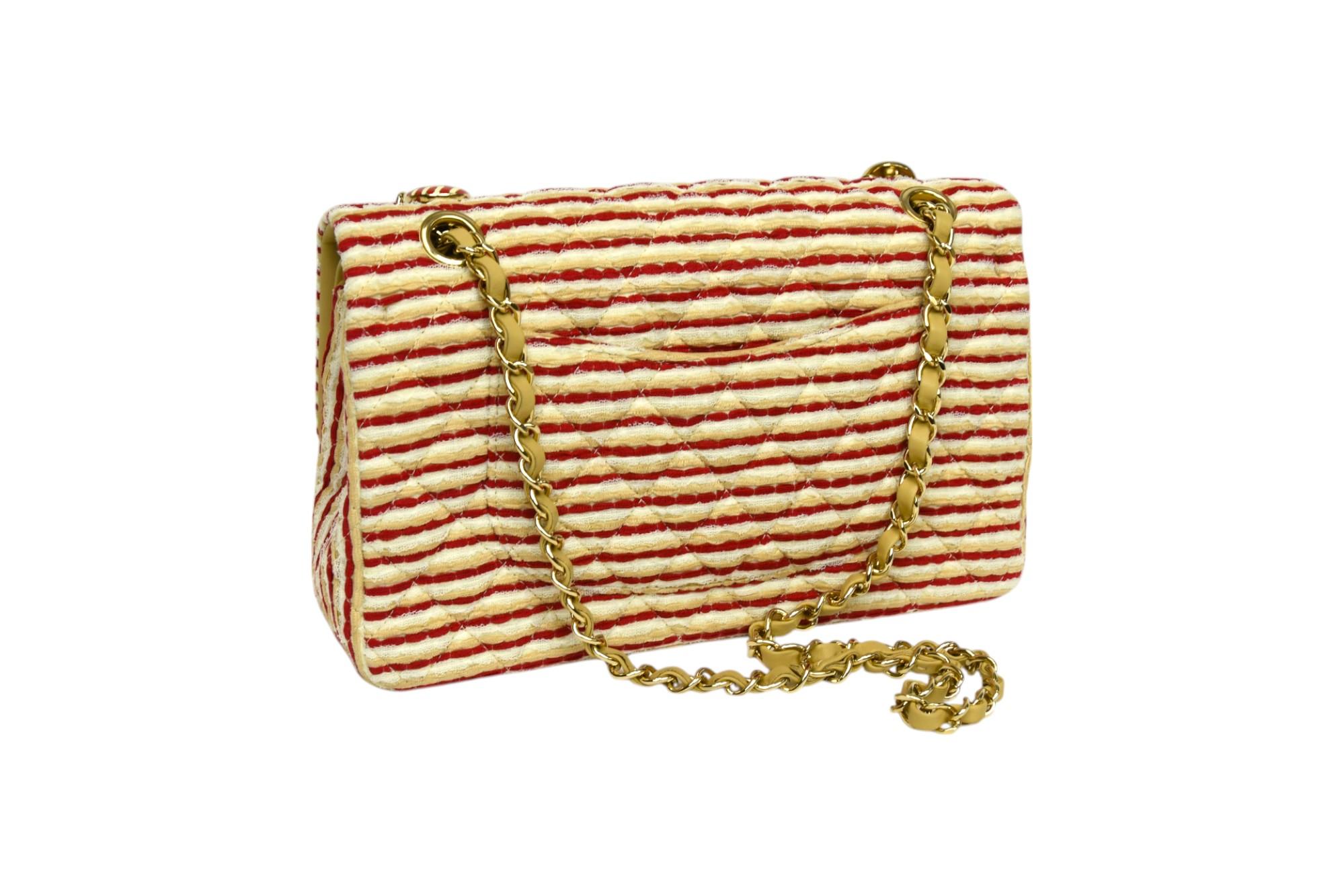 Ce saisissant sac à rabat moyen classique Chanel, issu de la collection 2014-2015, réinterprète la silhouette la plus emblématique de la maison avec une élégance ludique. Fabrice en tissu matelassé à rayures rouges et beiges, ce sac présente des