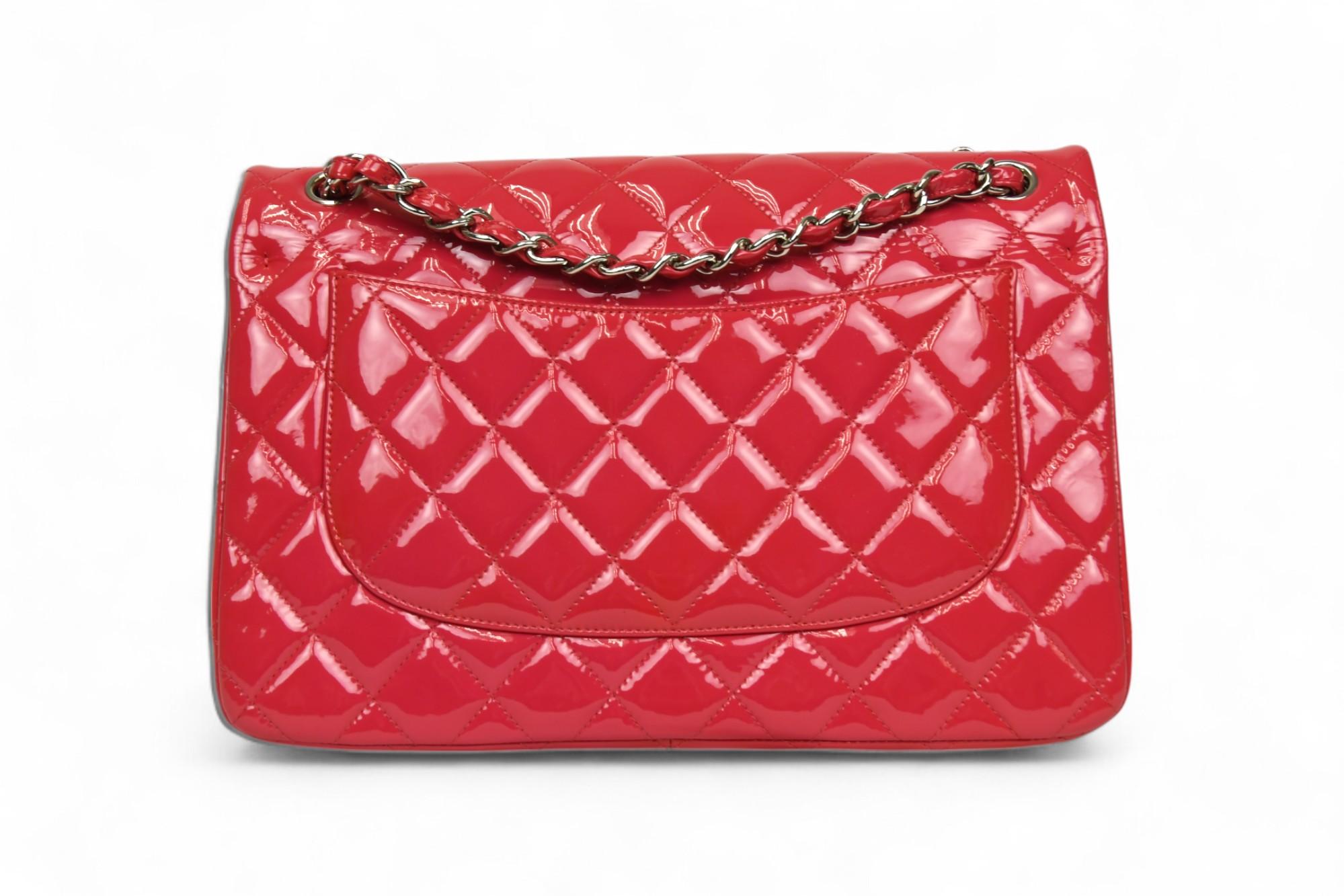 Una rivisitazione audace dell'iconica silhouette di Chanel, questa borsa Jumbo Collection con doppia patta è realizzata in vernice trapuntata color lampone e rappresenta un pezzo forte della collezione 2014. La finitura lucida e la struttura