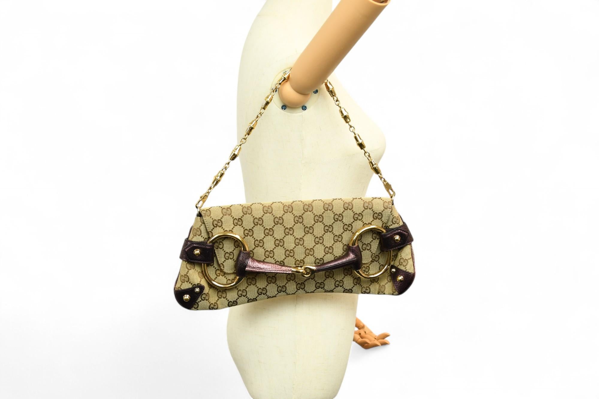 Diese Clutch mit Monogrammen von Gucci ist der Inbegriff zeitloser Raffinesse mit einem unverwechselbaren Reitermotiv. Die Tasche ist aus beigefarbenem GG Canvas gefertigt und verfügt über auberginefarbene Metallic-Lederakzente und ein übergroßes