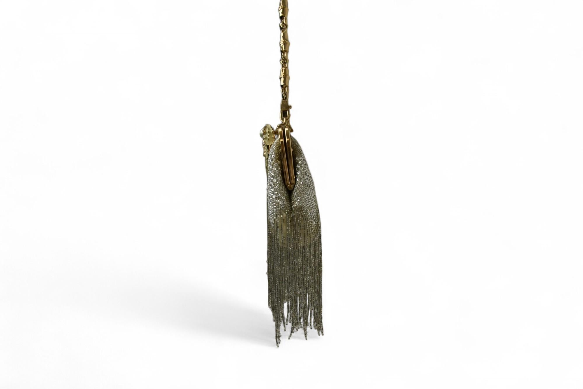 Artefact éblouissant de l'ère Tom Ford chez Gucci, ce sac du soir incrusté de cristaux est la quintessence du luxe glamour. Avec ses strass scintillants qui tombent en cascade dans une frange de perles dorées, il évoque l'opulence et l'audace du