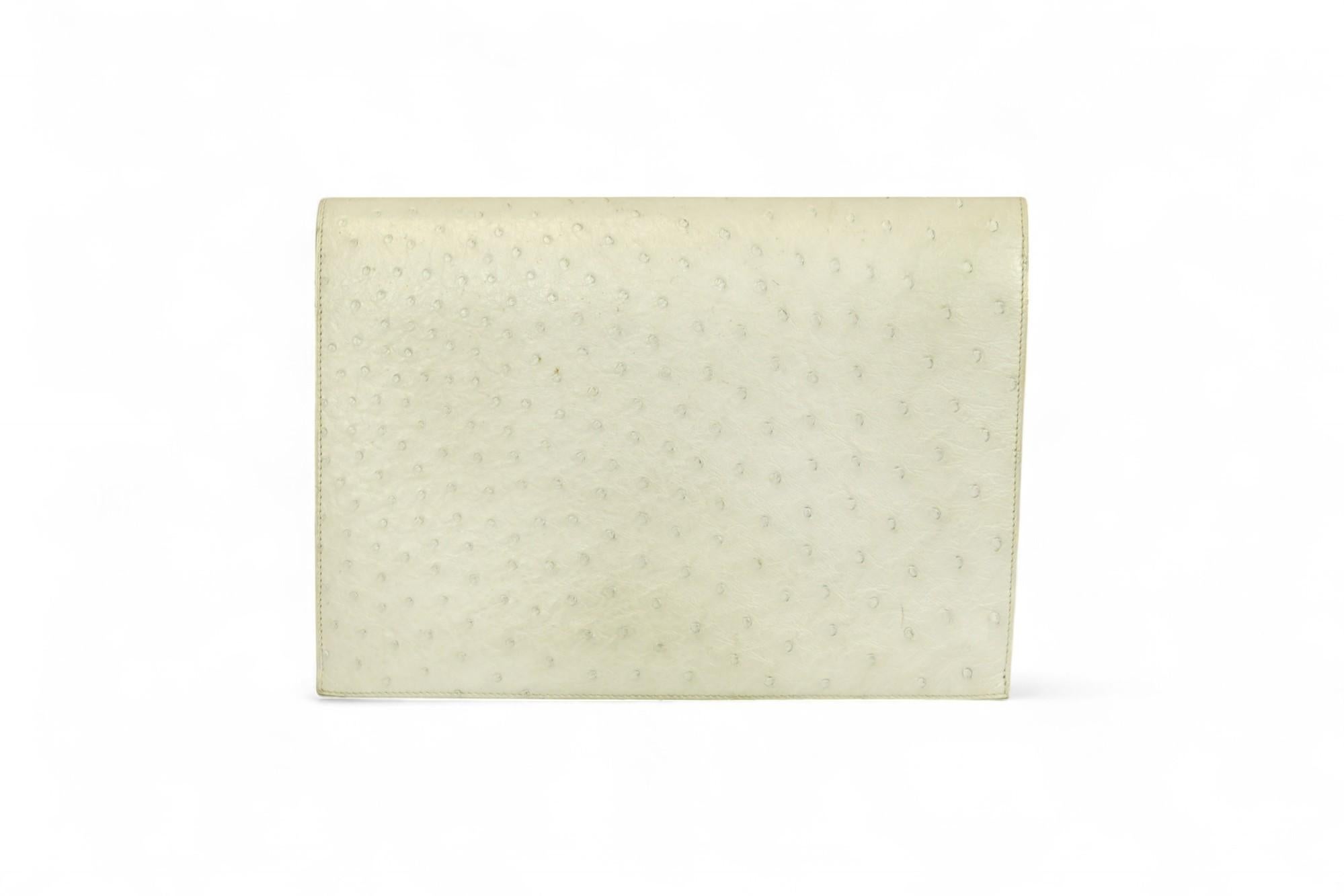 Diese Pre-Médor Clutch ist ein seltenes und frühes Beispiel für die Designentwicklung von Hermès. Sie ist aus exquisitem weißem Straußenleder gefertigt und mit goldfarbenen Pyramidennieten und doppelten Schnallendetails akzentuiert - ein Vorbote der