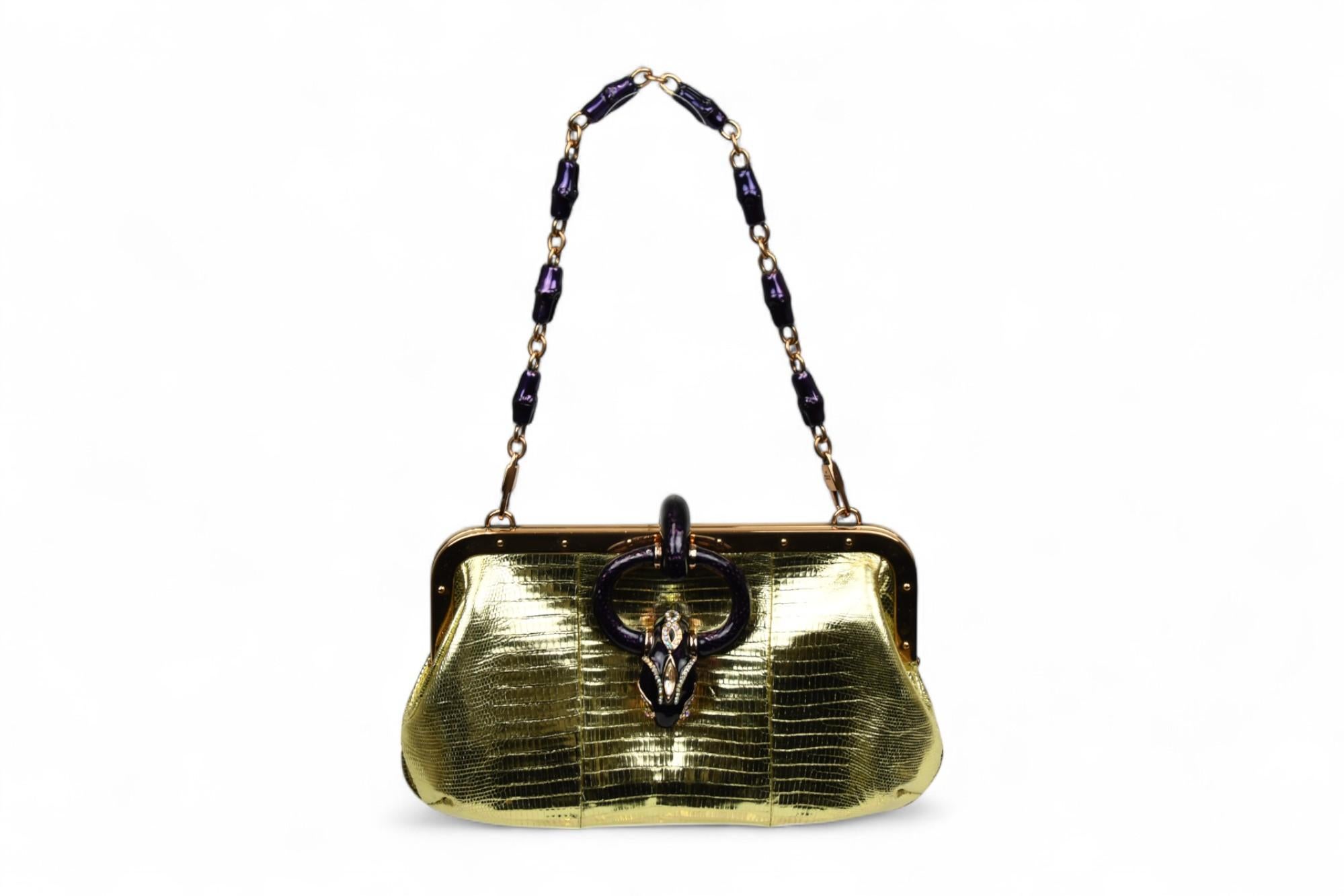 Capolavoro rarissimo del periodo di Tom Ford for Gucci, questa borsa con montatura in lucertola color oro metallizzato cattura l'apice dell'high glamour dei primi anni 2000. La silhouette strutturata è incorniciata da una metalleria in oro lucido e