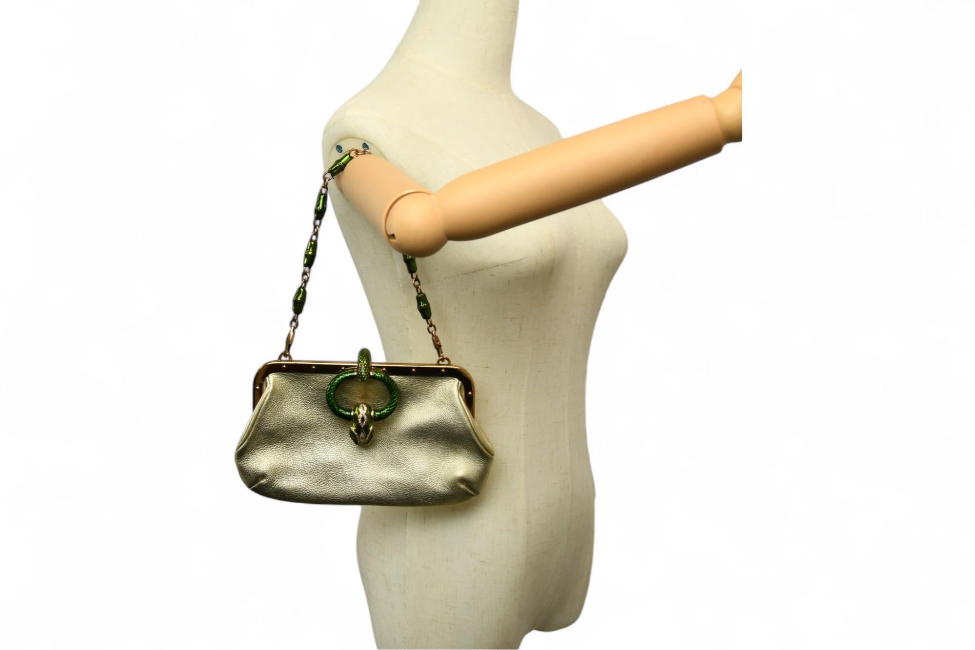 Création emblématique de la collection printemps/été 2004 de Gucci par Tom Ford, ce sac compact à armature en cuir métallisé est un symbole raffiné d'opulence et d'avant-garde. Le corps en cuir souple de couleur or champagne est ponctué d'un fermoir