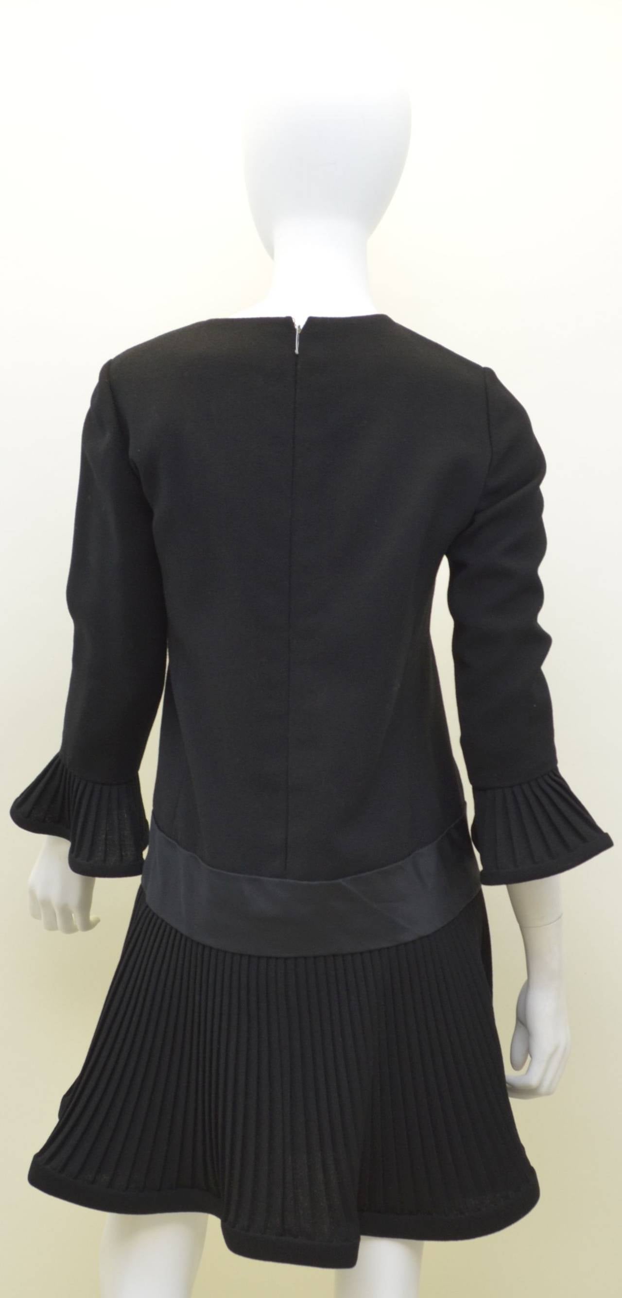 La mini robe Pierre Cardin présente une fermeture éclair au dos, des poignets et un ourlet plissés, une bande de satin autour des hanches et est entièrement doublée. 

Mesures :
Poitrine - 35
Taille - 33''
Hanches - 40
Manches - 20,5