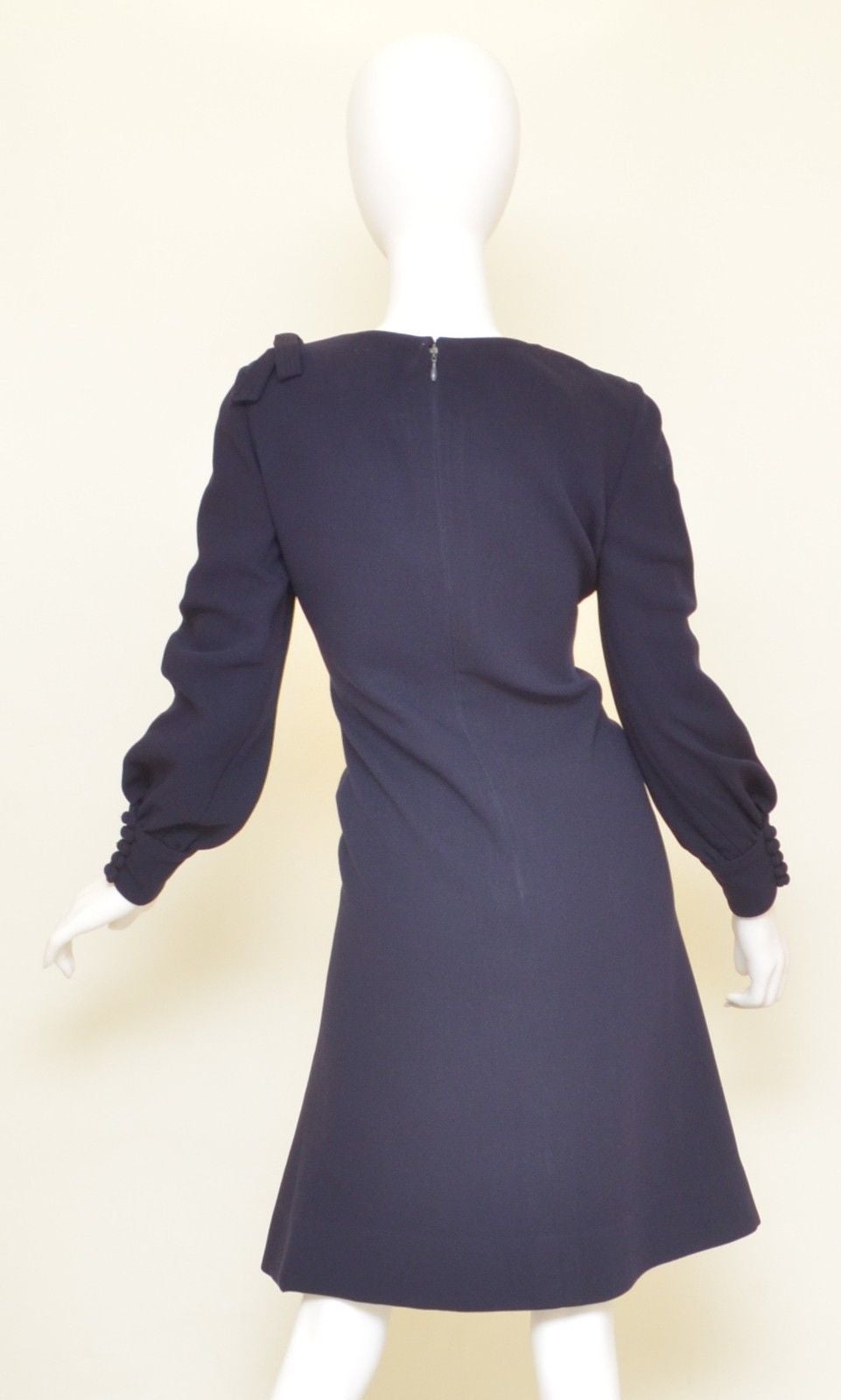 Vintage 1970's wool dress has a back zipper closure, button closures at the cuffs, decorative bow at the shoulder, A-line silhouette, and ruching at the sleeves. Dress has some normal wears to the buttons and some pulling to the wool material from