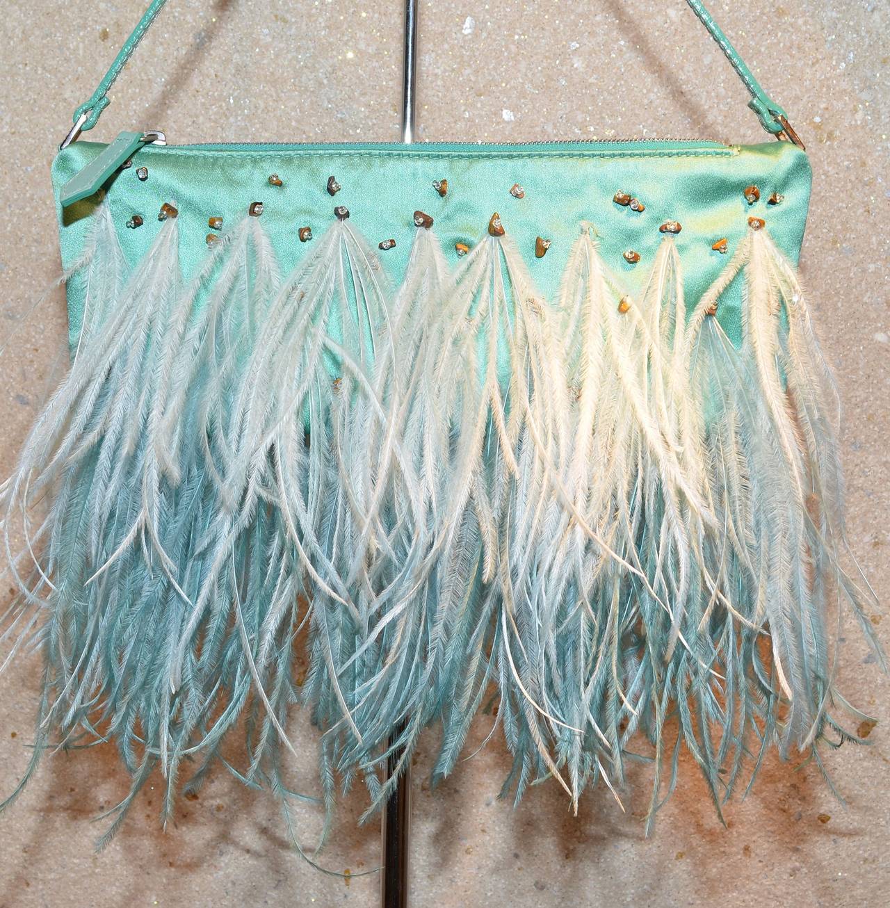 Valentino Garavani Aqua Blue Satin Beaded Ostrich Feather Evening Bag

Valentino evening bag features a zip top closure with a leather zipper pull, adjustable leather handle with silvered metal buckles that feature encrusted rhinestones, Ostrich