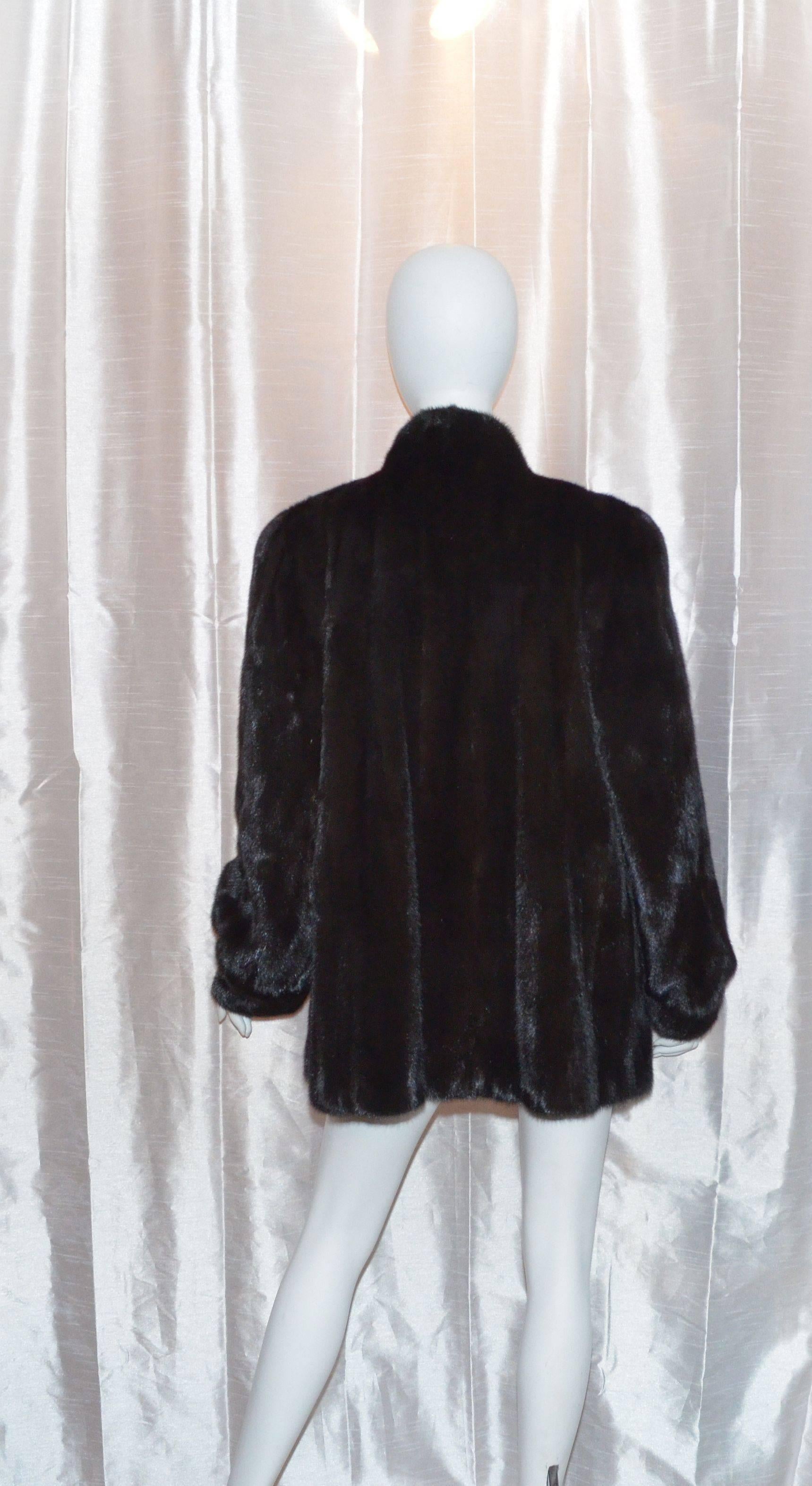 Hip length Revillon mink coat is fully lined and has two pockets at the waist. Color is dark black brown. Estimated size is a US 14-16.

Measurements:
Bust - 50''
Sleeves - 26.5''
Shoulders - 18''
Length - 32''