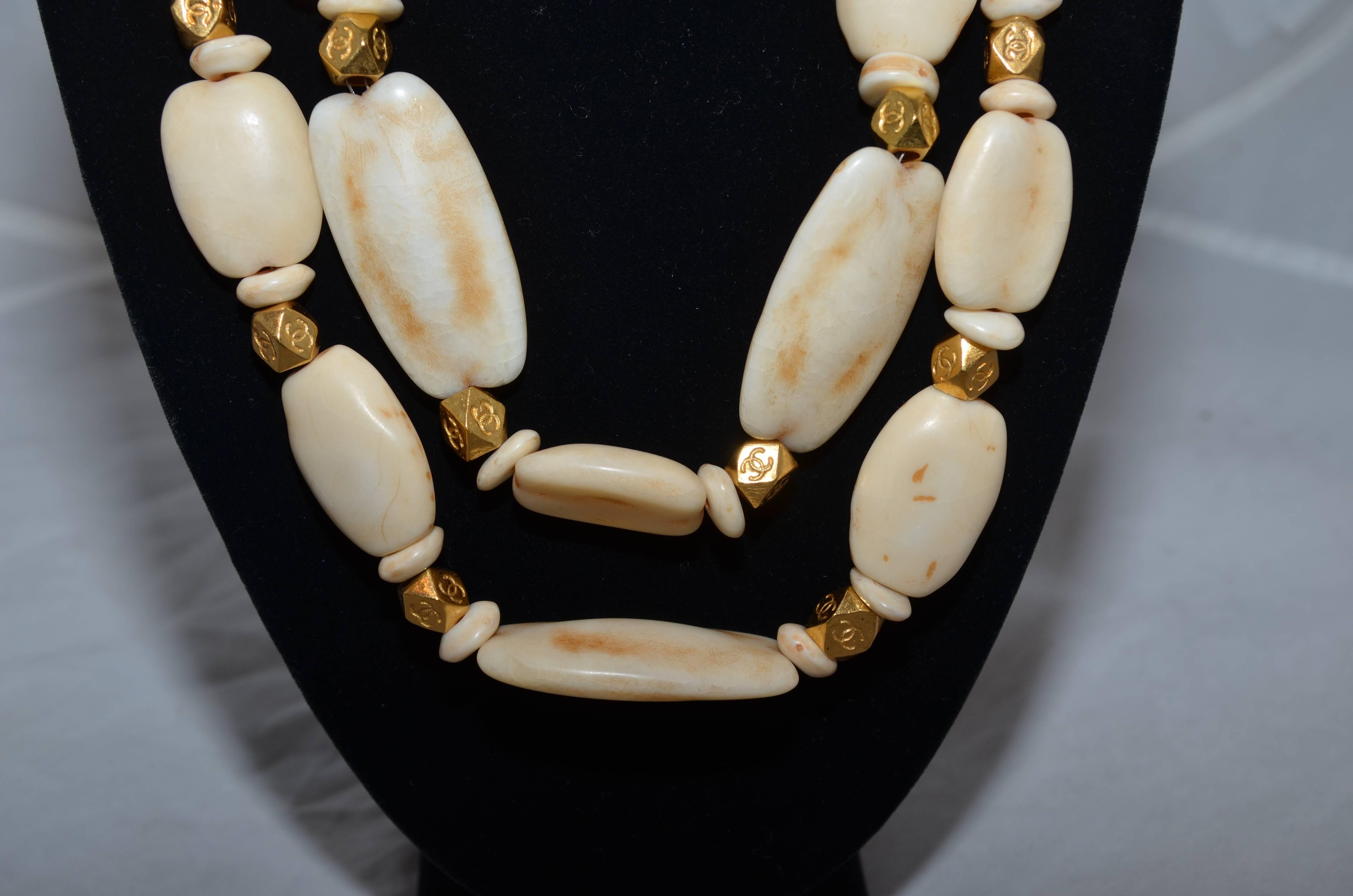 Chanel necklace from 1996 Spring collection with a double strand of chunky faux ivory beads and CC engraved gold-tone spacers. Necklace has a chain-link and hook closure for sizing. Made in France.

Length - 20''