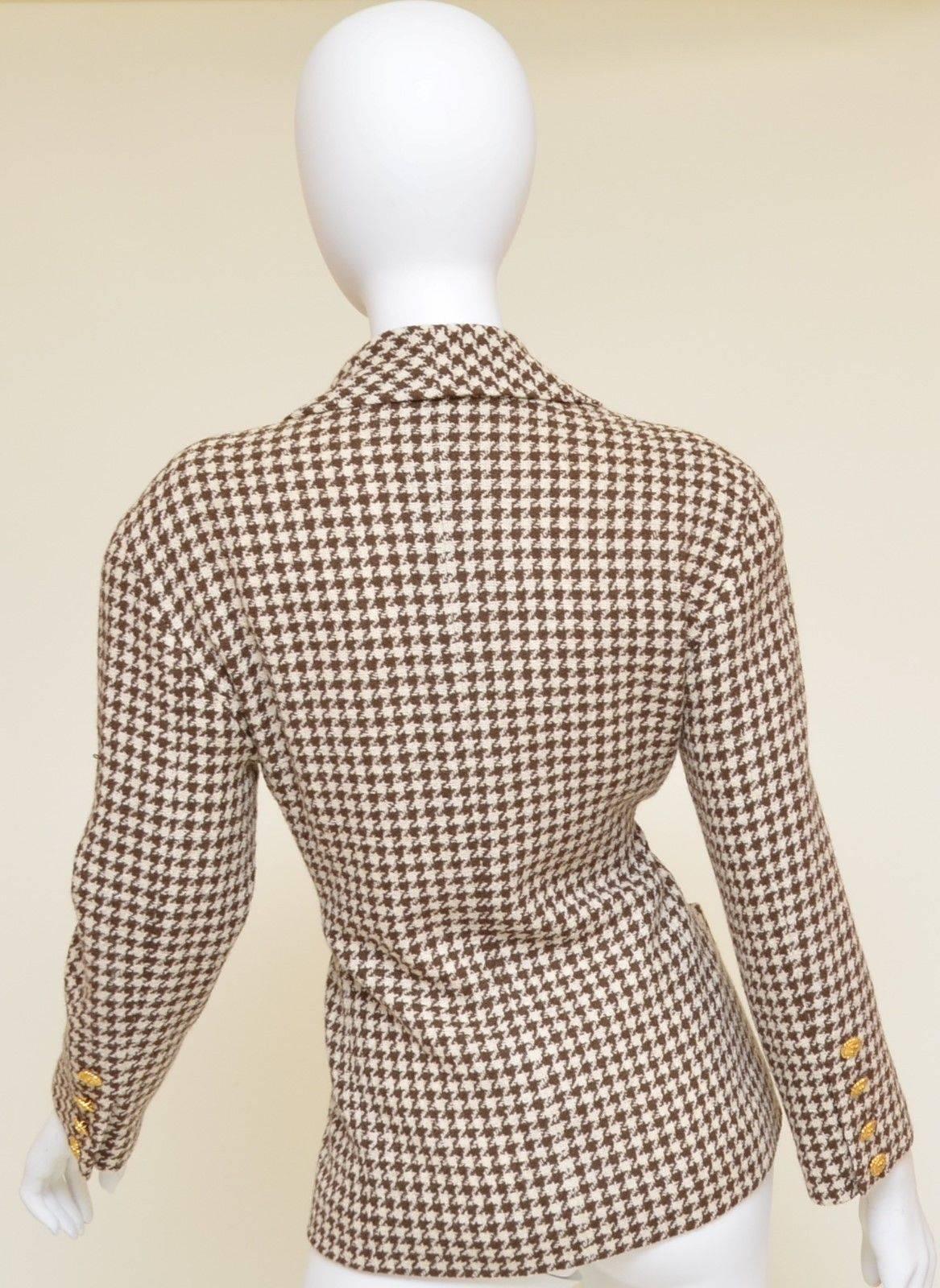 Chanel Boutique jacket features gold-tone 'CC' button closures at the front and along the cuffs, brown and ivory houndstooth pattern knit throughout, bow-tie pattern print underneath the collar, blazer has a total of four slip pockets; two at the