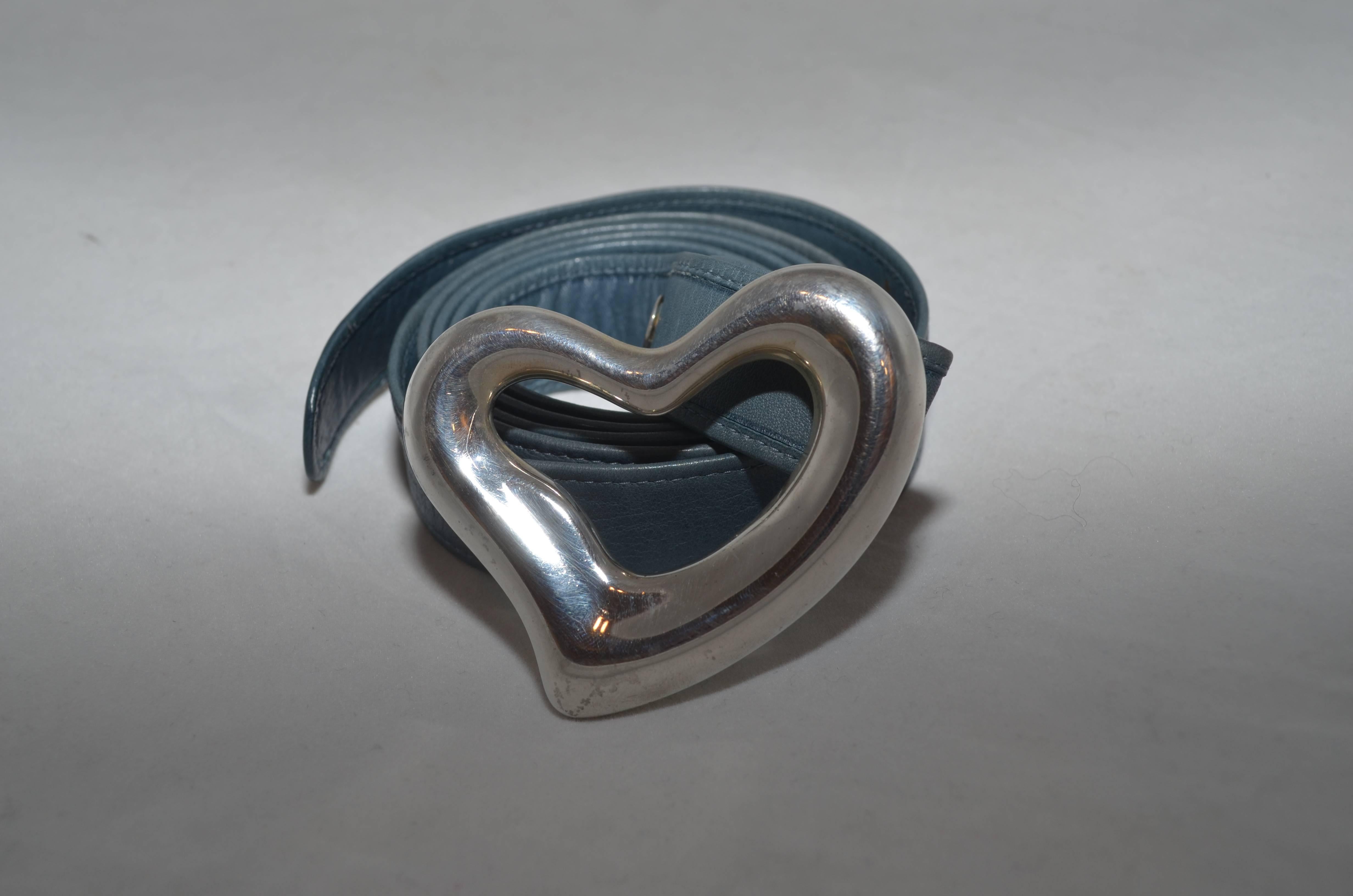 Tiffany & Co Elsa Peretti 1975 Sterling Silver Open Heart Buckle Leather Belt

Tiffany & Co. Elsa Peretti sterling silver open heart buckle and a blue leather belt strap that is 2 centimeters wide, and is 43 inches long. Silver heart is stamped