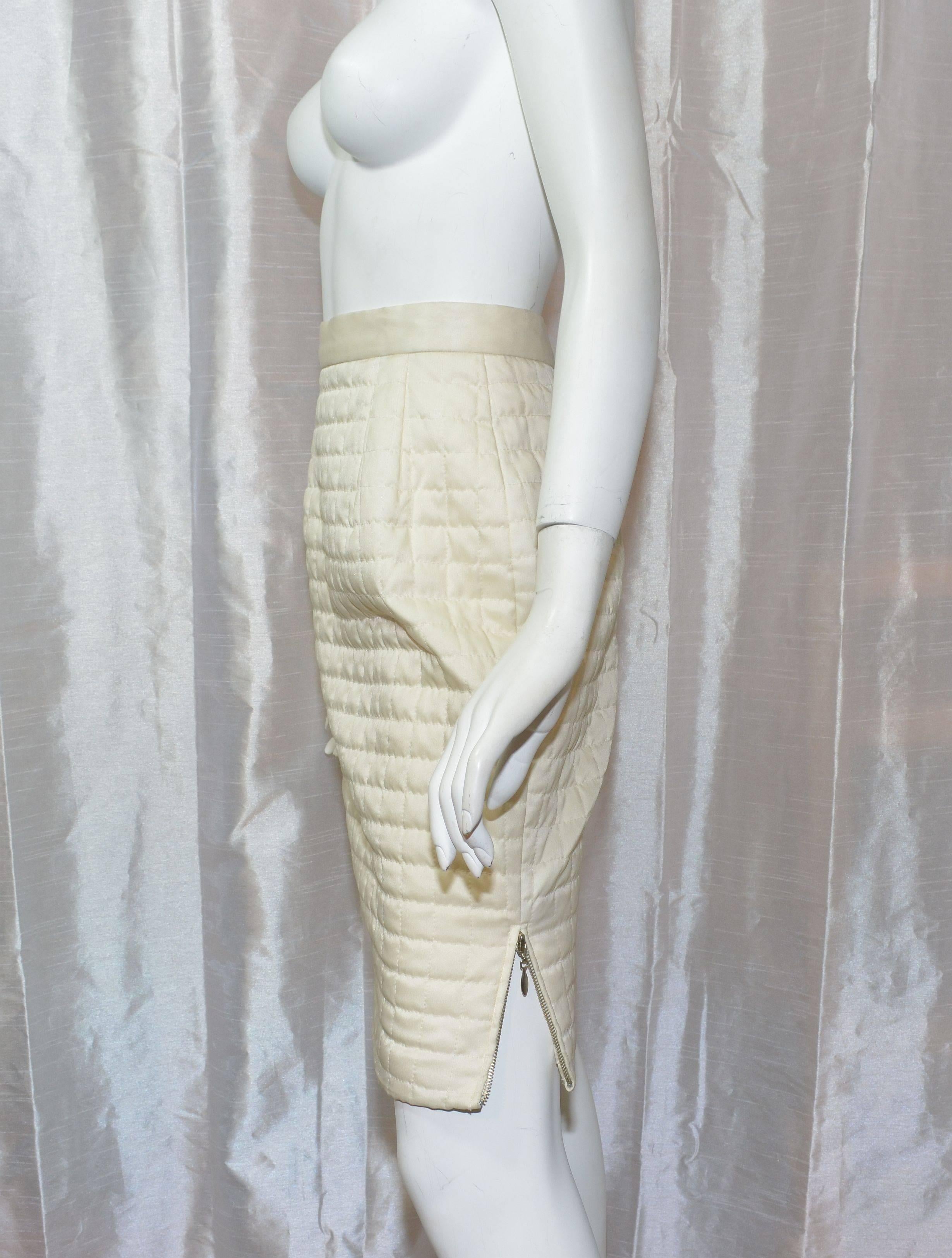 Chanel skirt featured in an ivory-colored satin fabric, with a back zipper closure and a zipper along the left hem . Skirt is fully lined. Measurements: waist - 25'', hips - 34'', length - 21.5''