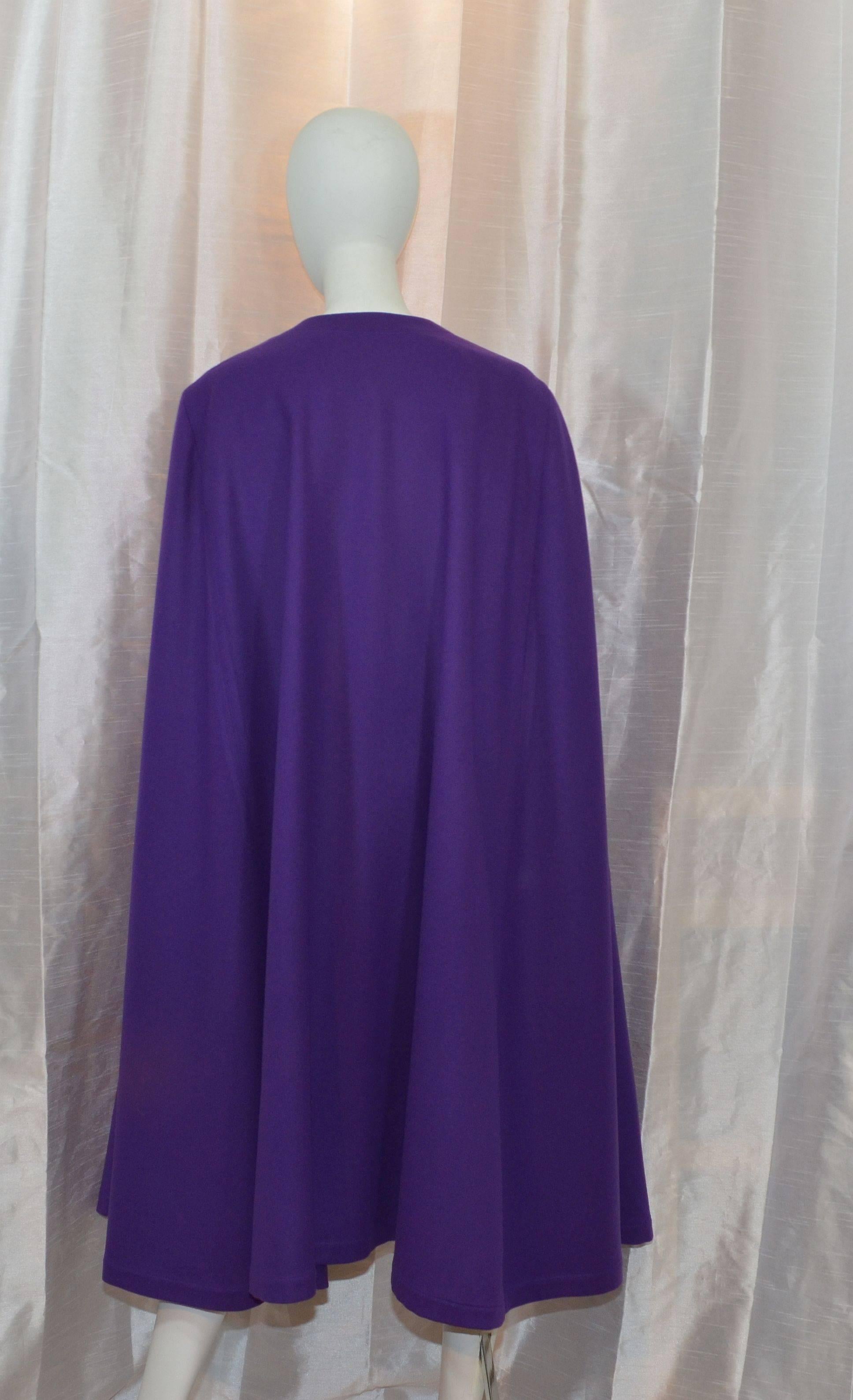 Iconic Vintage Yves Saint Laurent cape featured in purple has one button closure at the neck, 100% wool, labeled size 38, and made in France. Length measures: 45''