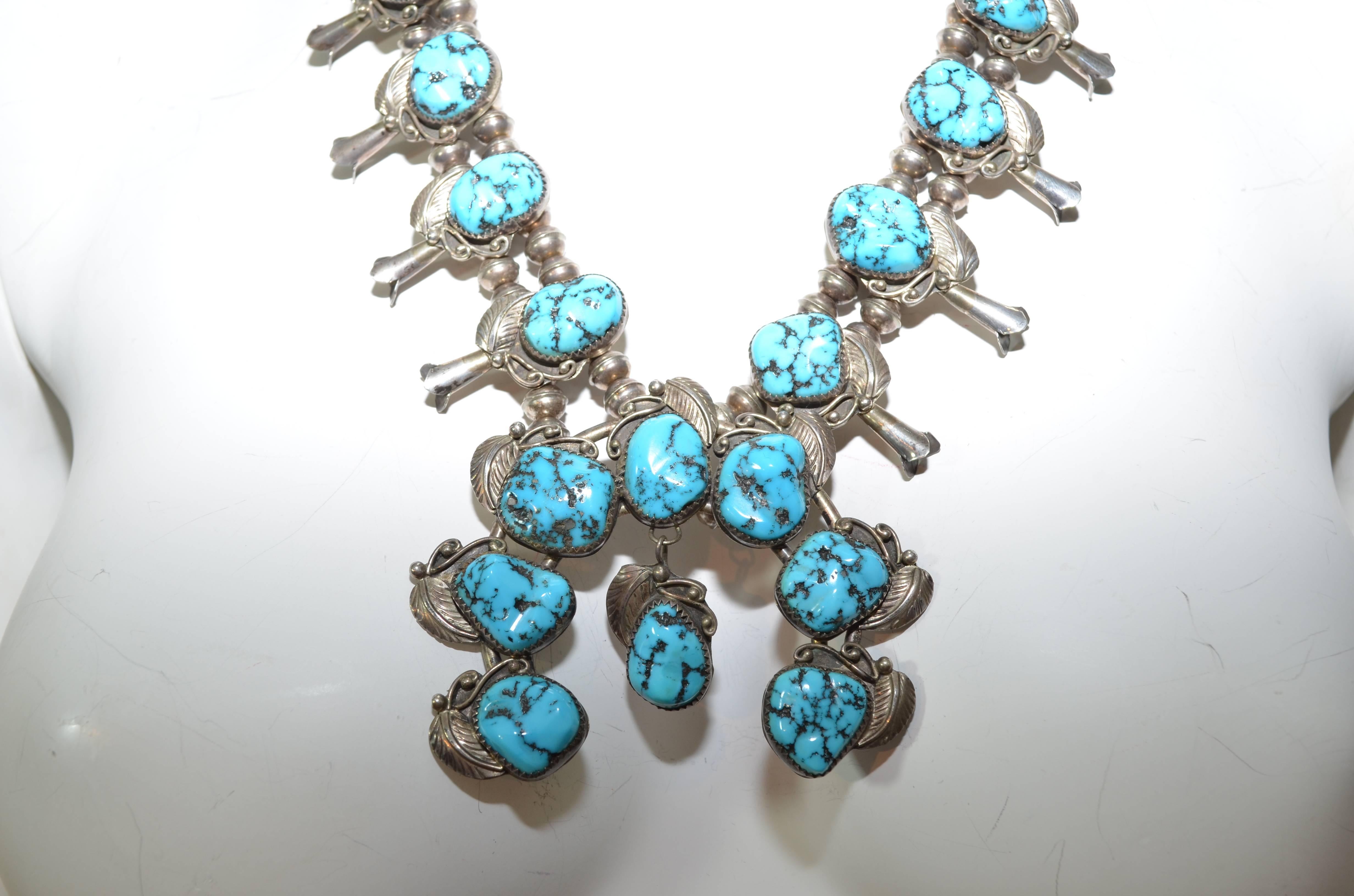 1950s squash blossom Navajo necklace in sterling silver with massive Bisbee turquoise stones. Beautiful ornate details in leaves. Excellent original condition, good patina! Marked STERLING. Hook closure. Length= 14'', weight = 120 grams

In Native