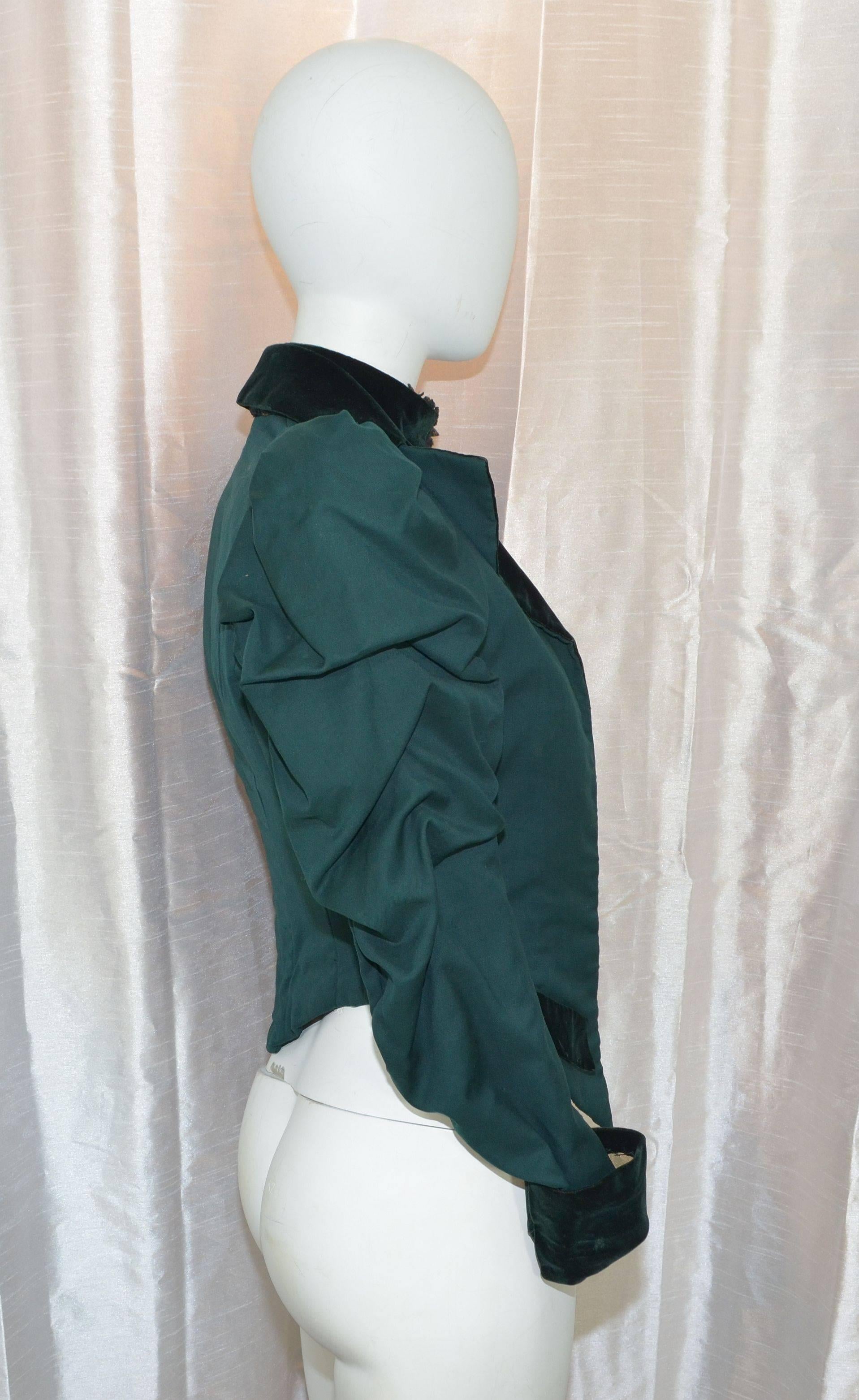 Vintage Victorian jacket featured in deep green with velvet trimmings, hook-and-eye closures along the front as well as hook closures for the built-in corset. Exquisite sleeve detail. Decorative velvet flap pockets at the hem. Would guess this to be