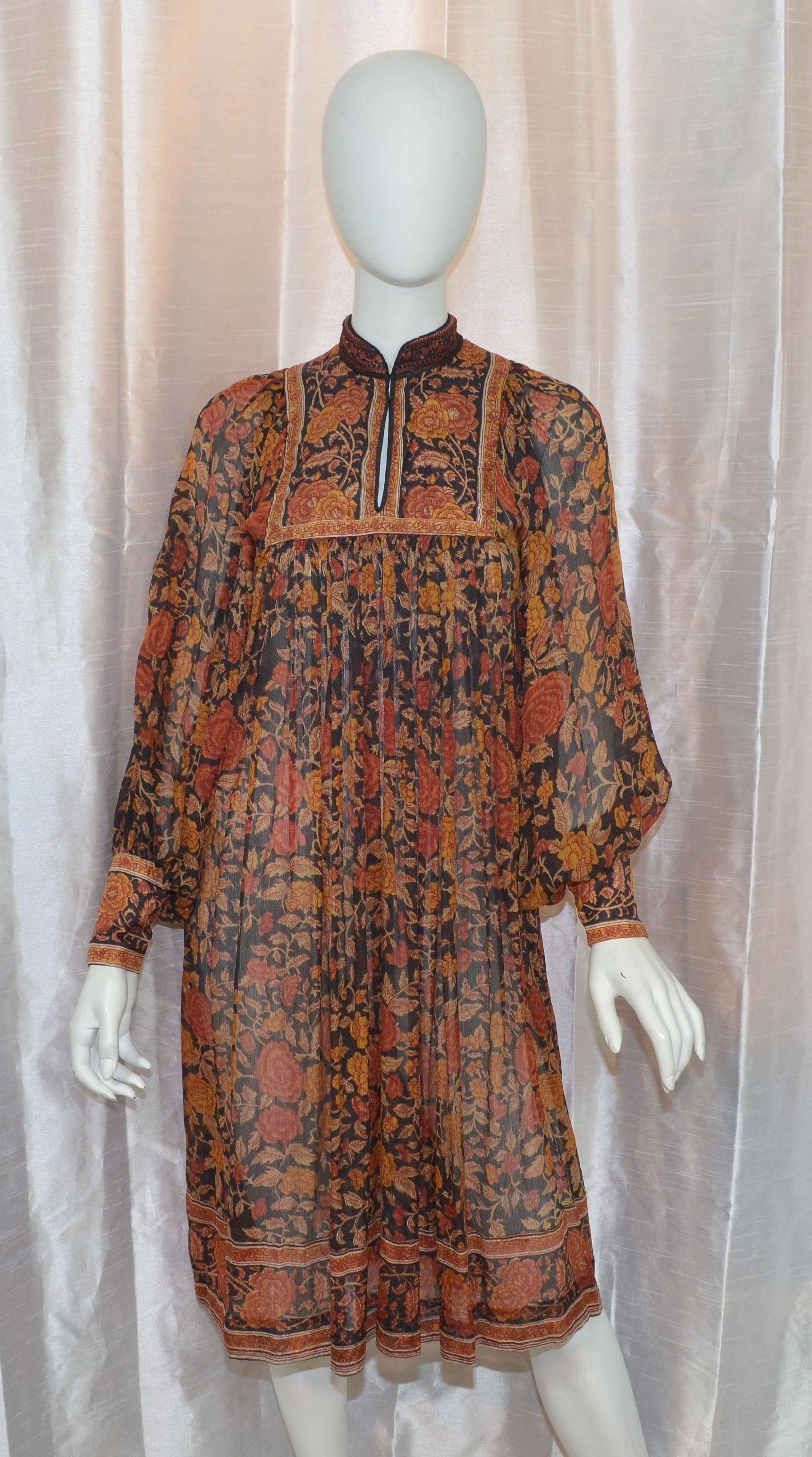 Ritu Kumar for Judith Ann boho style dress in 100% silk with a floral print in a variation of maroon, tan, and brown colors on a black background. Dress has cuffed sleeves with button fastenings and a hook-and-eye closure at the neck. Loose and