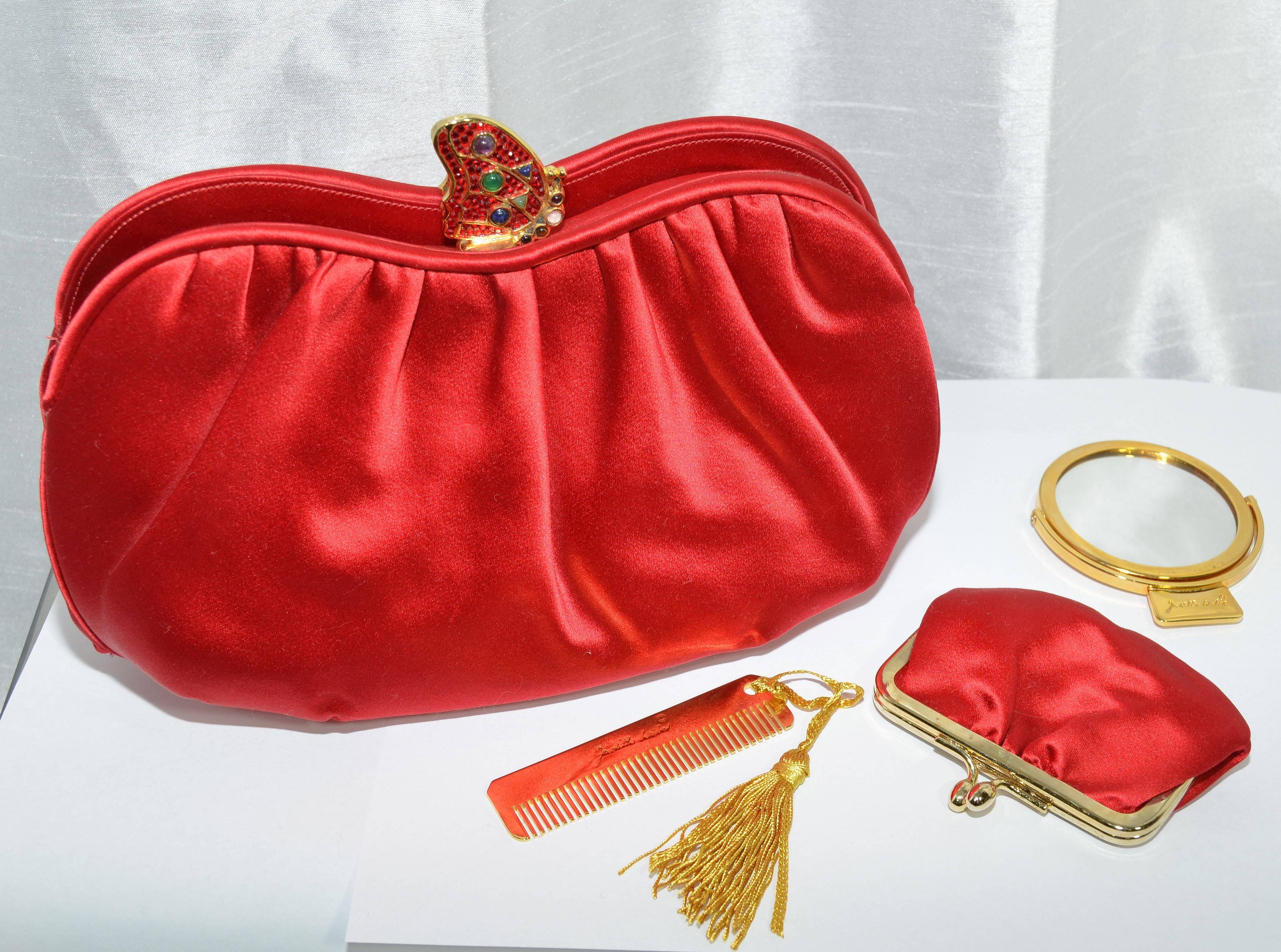 Gorgeous Judith Leiber clutch featured in a blue red satin fabric with a slightly ruched opening. There are three separate compartments with the center compartment including one zipper pocket and one slip pocket, with a gold-tone jeweled metal