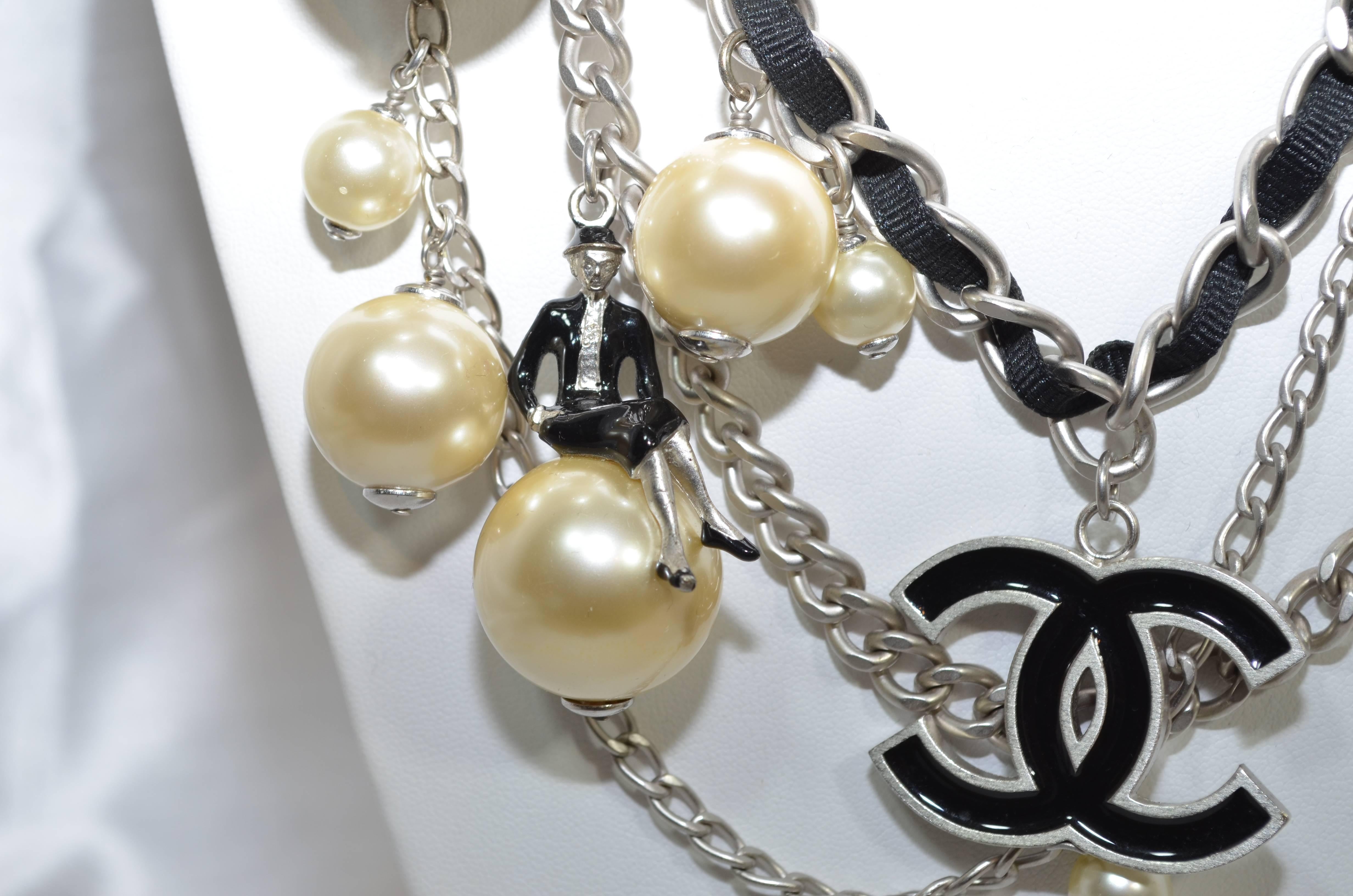 Rare Chanel Spring 2014 Collection Coco Over the Moon belt with CC logo charms, silver-tone multi-strand chain-links, and pearl embellishments, several pearls have Coco Chanel figure on with enamel suit sitting on them. Hook closure. Approximate