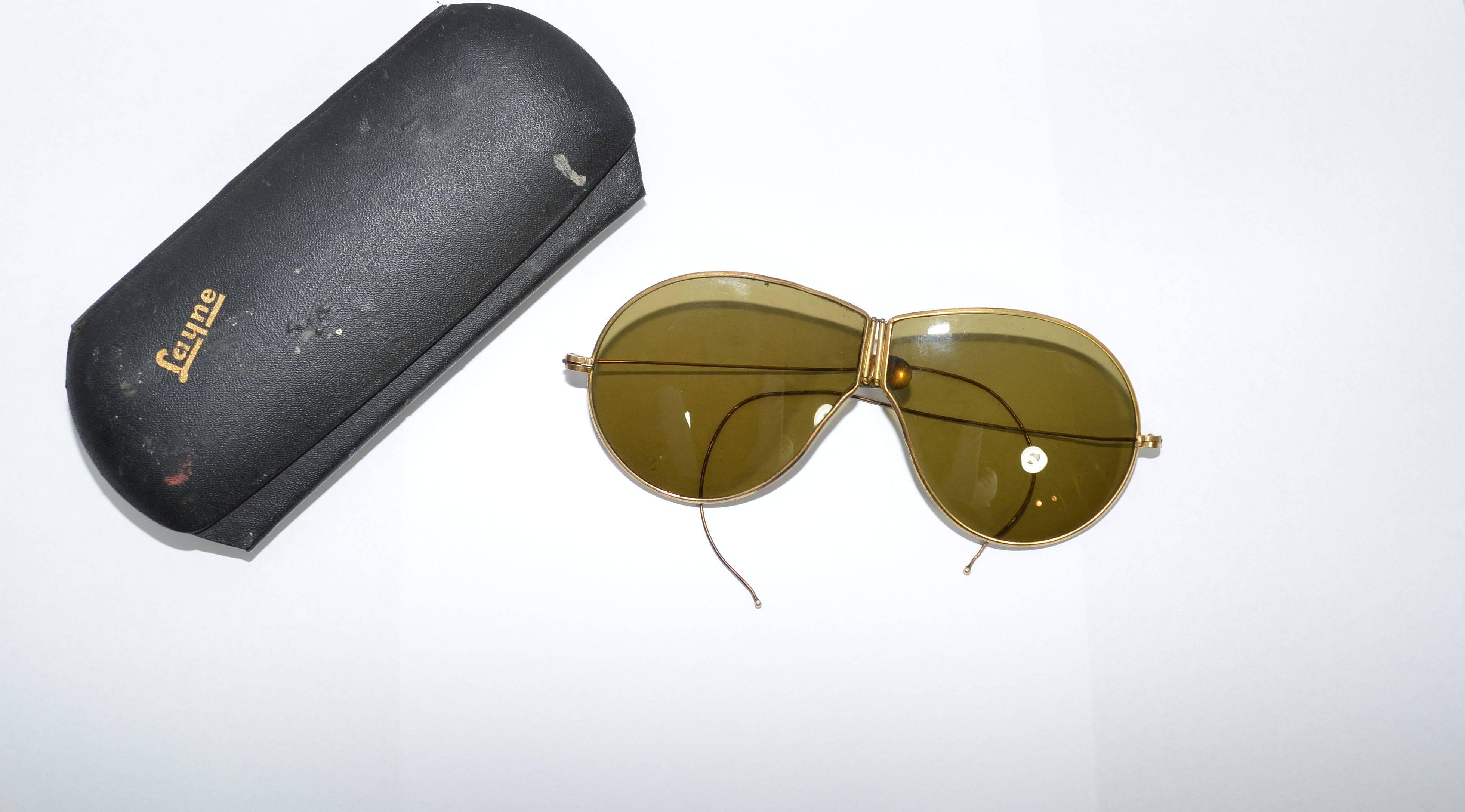 Vintage folding aviator sunglasses with olive-colored flat lenses. These sunglasses fold up into the size of one lens when not in use, and have an antique gold metal frame that folds in the center and on the temples for easy storage. 

Temples