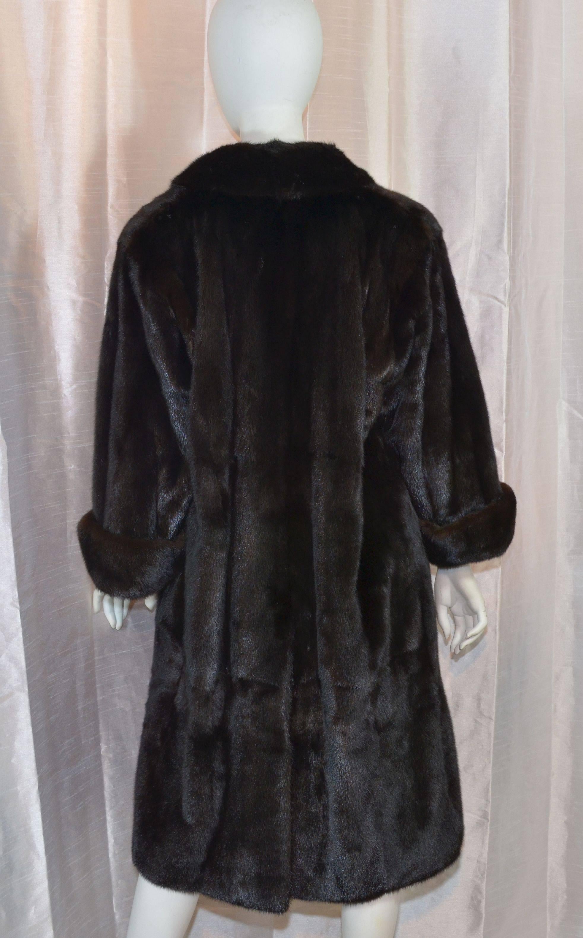 Yves Saint Laurent vintage 1980's mink coat is featured in a dark, almost black, brown mink fur with one button fastening, cuffed sleeves, full YSL logo jacquard lining, and two slip pockets at the hips. Coat is in excellent condition with no signs