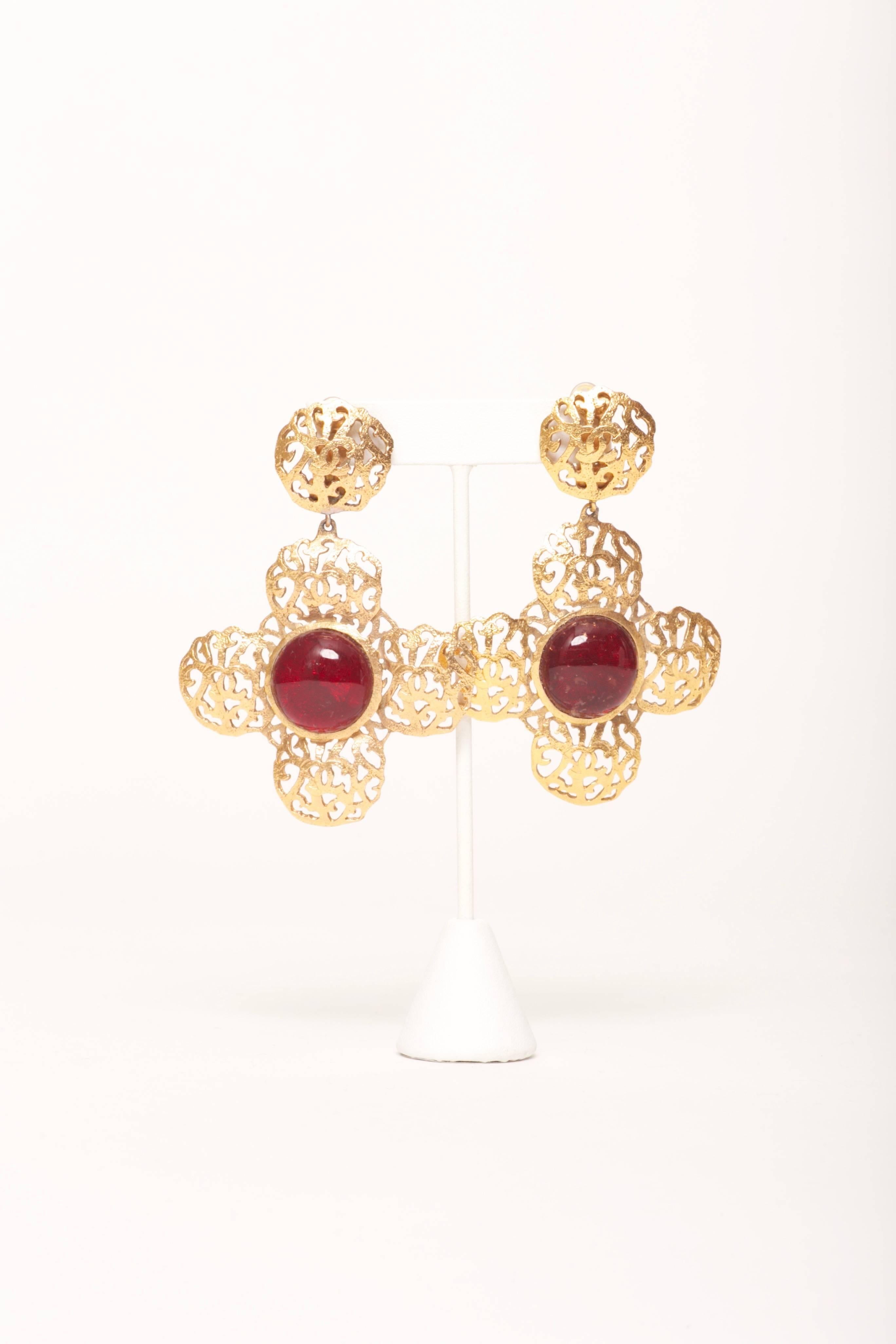 Chanel XL Gripoix Cross Earrings Collection 25 from 1987

Gold tone metal filigree clip on earrings with CC logos throughout. Reddish brown Gripoix poured glass centers that appear slightly darker when not in direct light. Large in size. Rare and