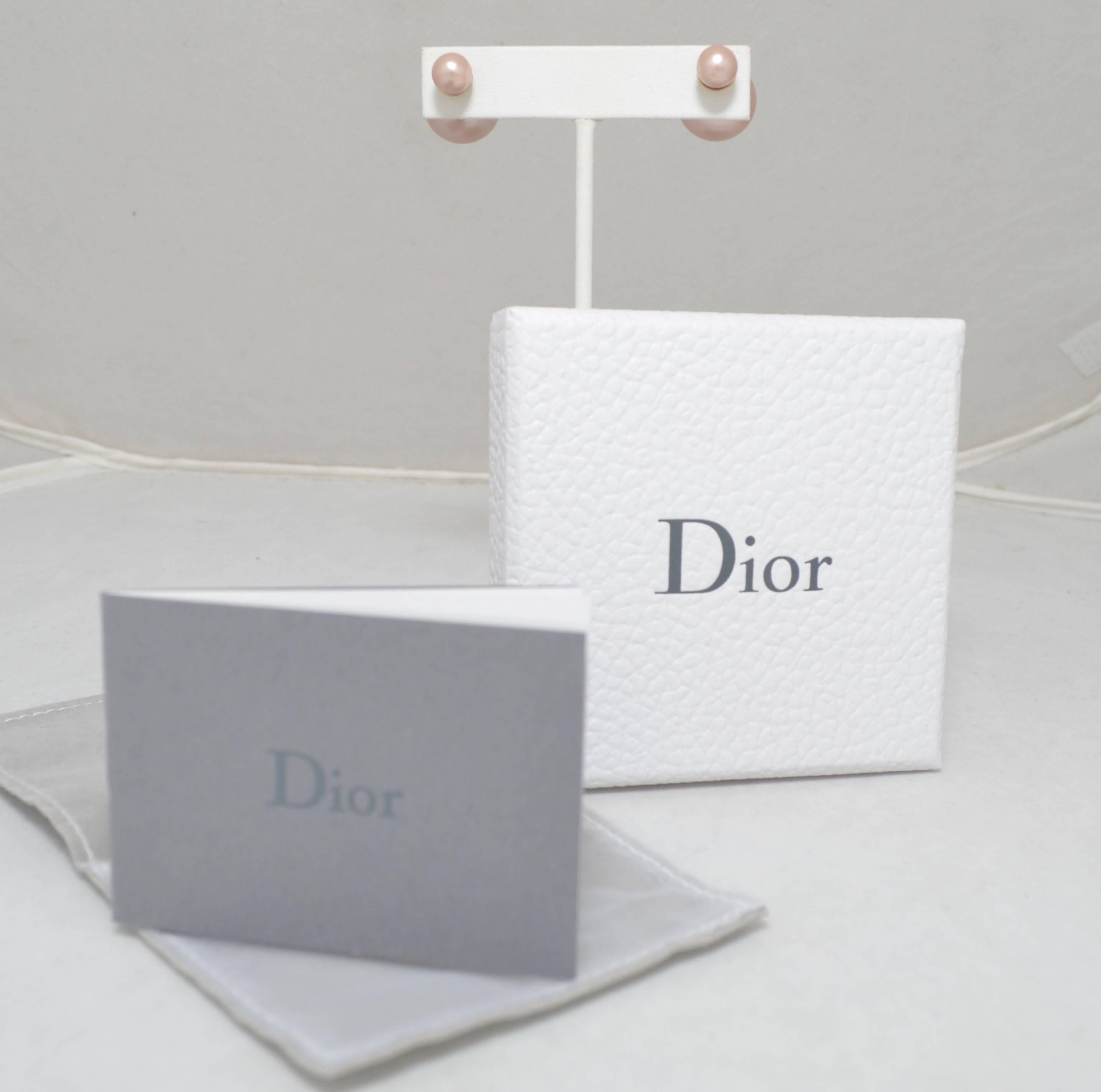 Mise en Dior Tribal earrings. Champagne colored pearl resin beads in asymmetrical sizes. The small pearl rests on the ear while the largest is behind the lobe. Earrings stamped Dior on metal portion of larger ball.
Dior jewelry box, pouch and care