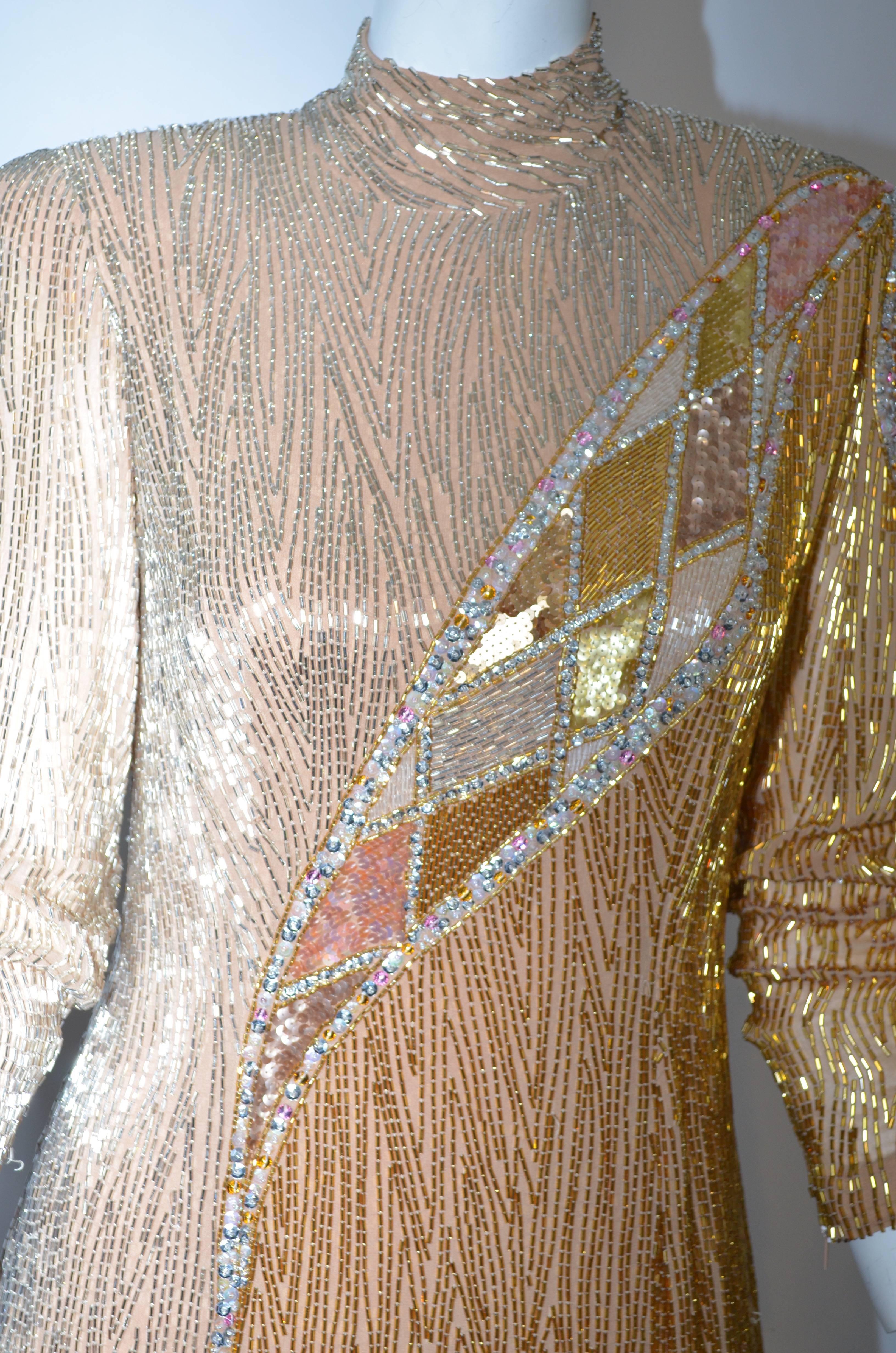 Exquisite Bob Mackie 1980's gold fringe beaded dress with hi-lo hem and 3-4 inch fringe on the lower 16 inches of the dress. Silver and gold bugle beads on nude silk chiffon with silver and pink sequins on design detail. Long fitted sleeve with