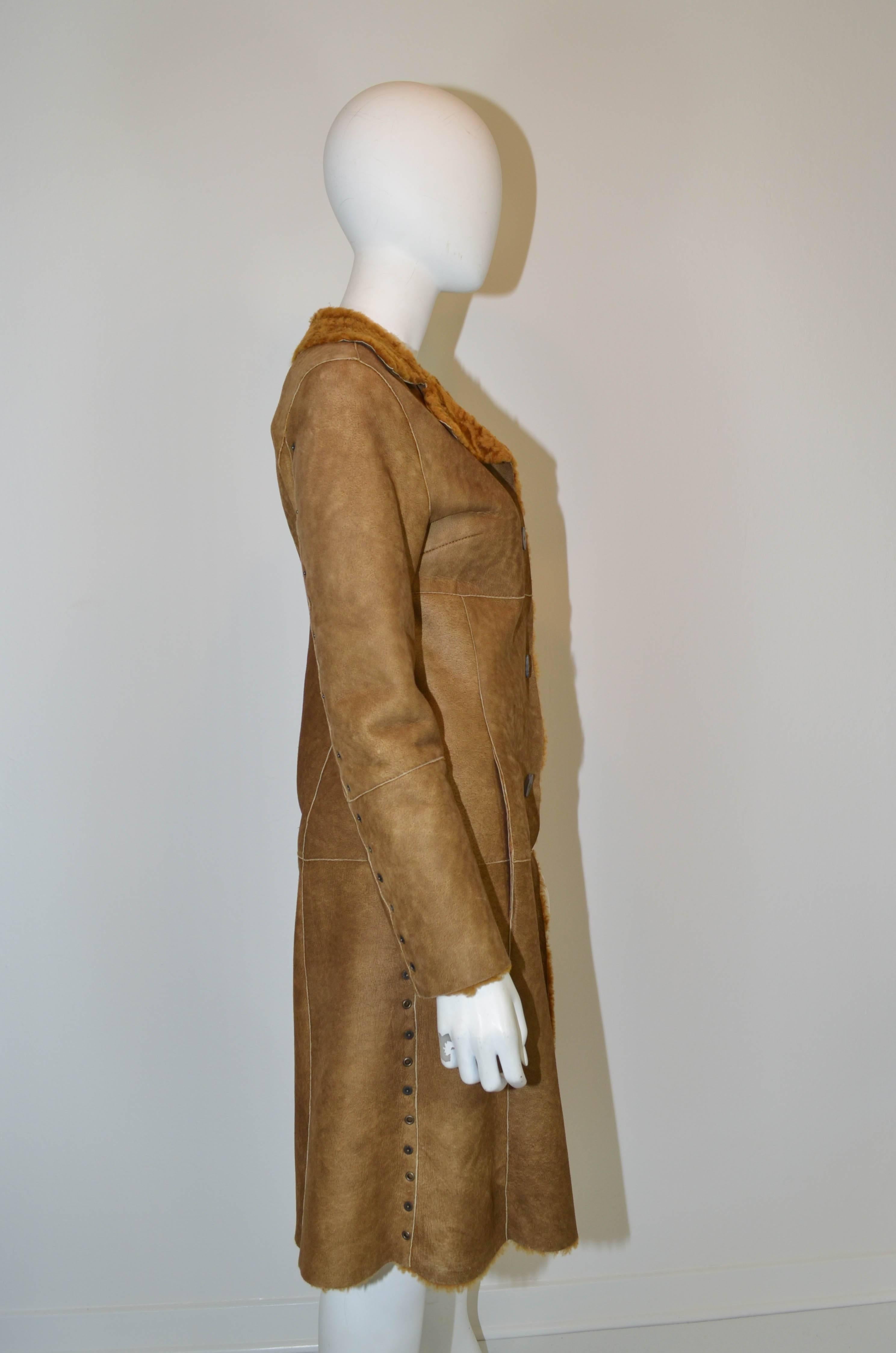 Beautiful Dolce and Gabbana D&G shearling coat in a stunning golden brown. Coat buttons down the front with horn buttons. Features metal snaps and grommets down the sides and along the outside of the sleeve. There are 2 hidden side pockets at hip