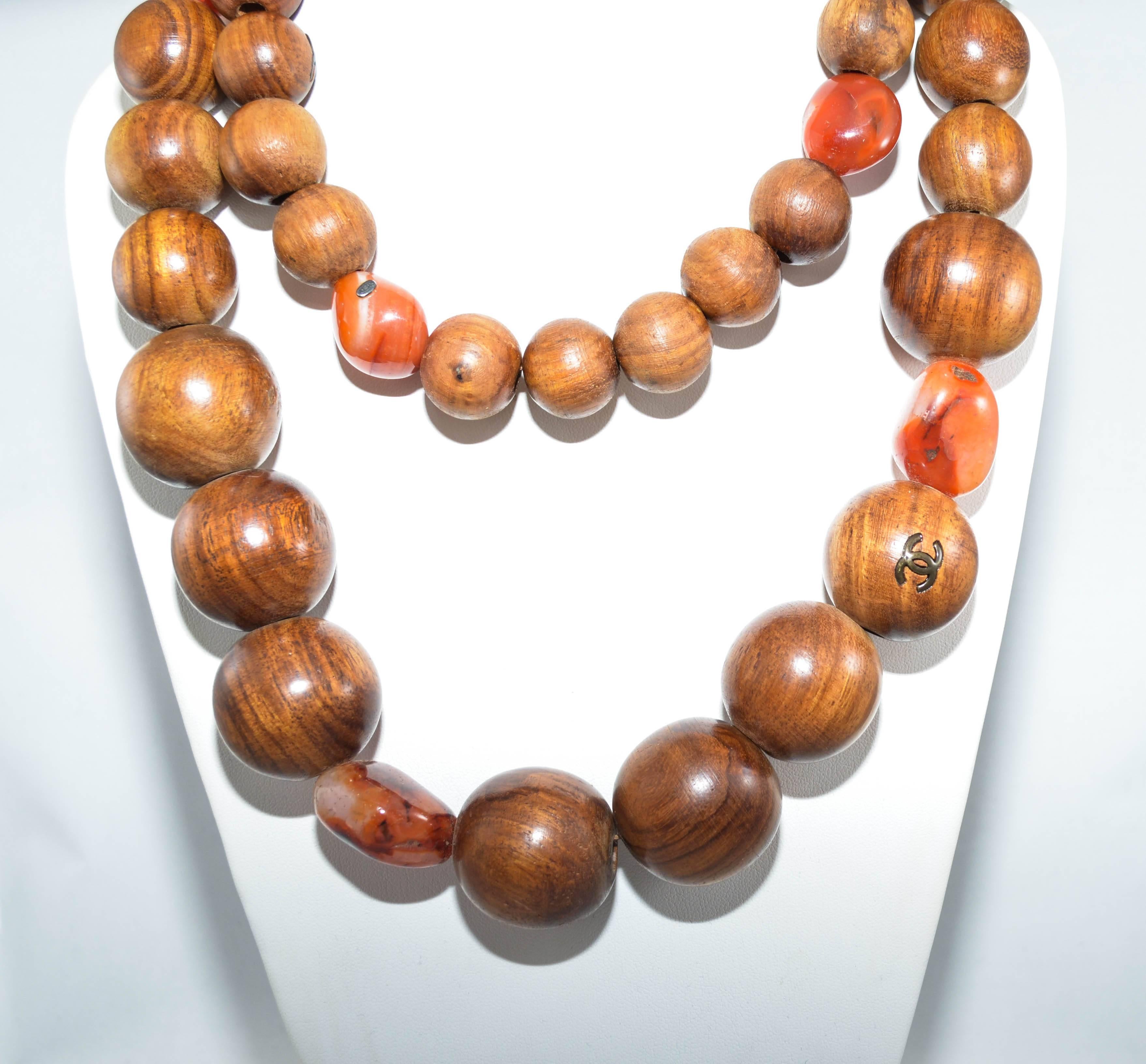 Vintage wood bead Chanel necklace with CC logo embedded in the wood. Graduated wood beads interspersed with tumbled stones form a 46 inch sautoir. 

Measurement in inches:
Length: 46
Drop: 20