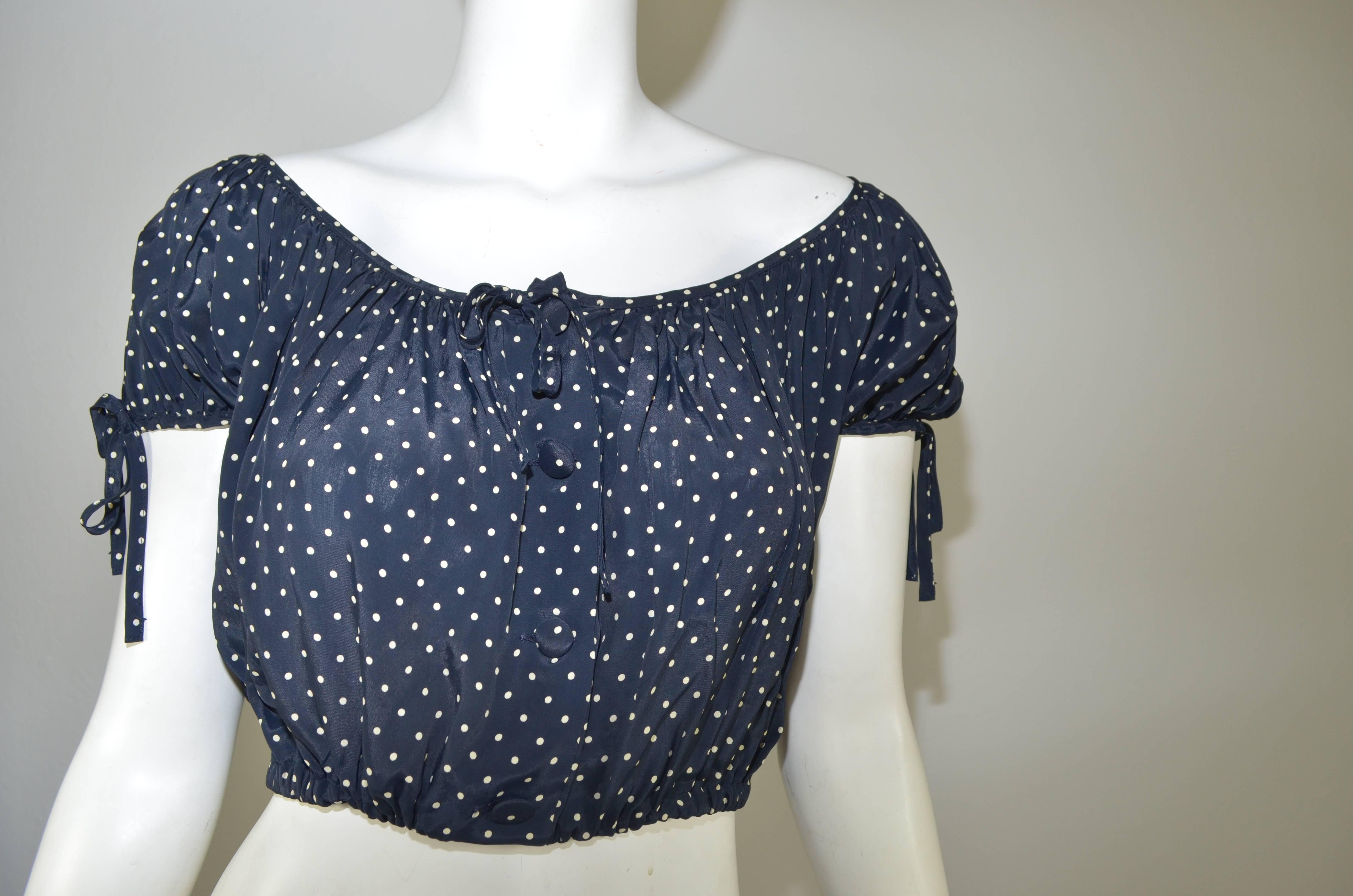 Moschino Cheap & Chic dark navy and white polka dot crop top peasant blouse made from 100% rayon with faux ties at sleeves and center front. Four working fabric covered buttons down front. Non opening bottom with elastic. Elastic at sleeve openings.