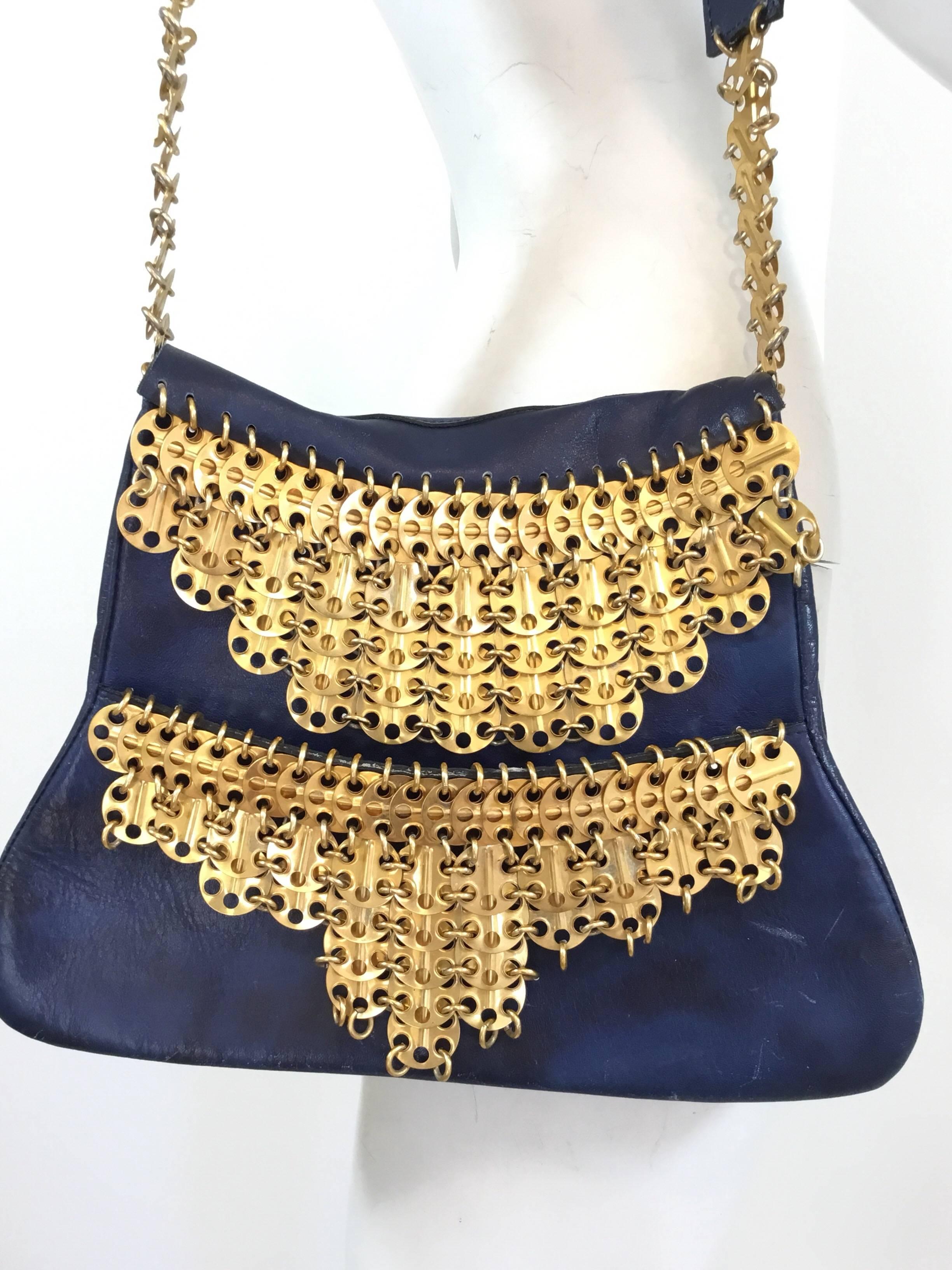 1960’s production RICAF Paco Rabanne bag featured in blue leather with gold disks. Bag has two separate compartments and a flat leather shoulder handle attached by gold disks. Bag shows some wears to the leather with spots of discoloration and