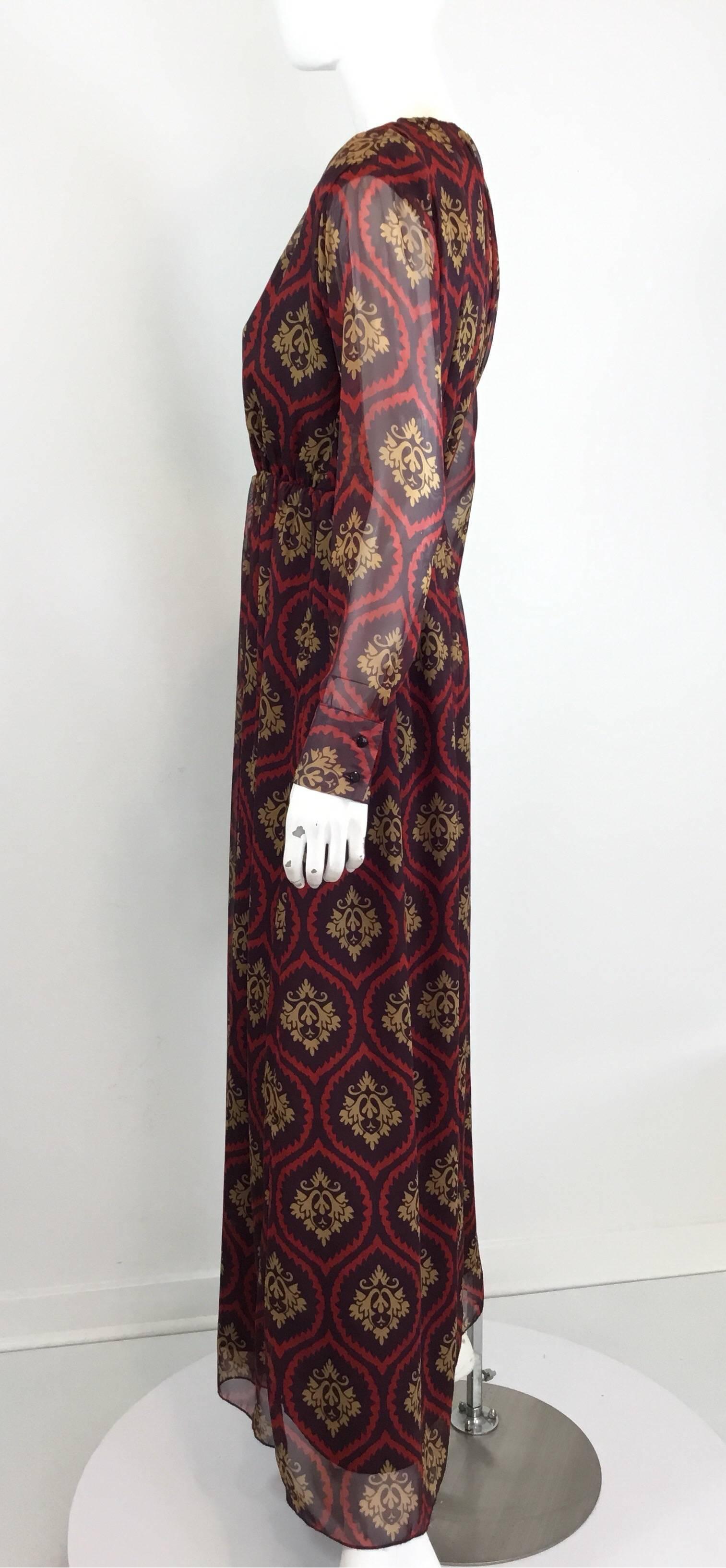 Gucci maxi dress featured in maroon with a red and tan print, plunging neckline, elastic band around the waist, and button closures for the sleeve cuffs. Made in Italy, labeled size M. Fully lined. Dress is in excellent condition with a few snags