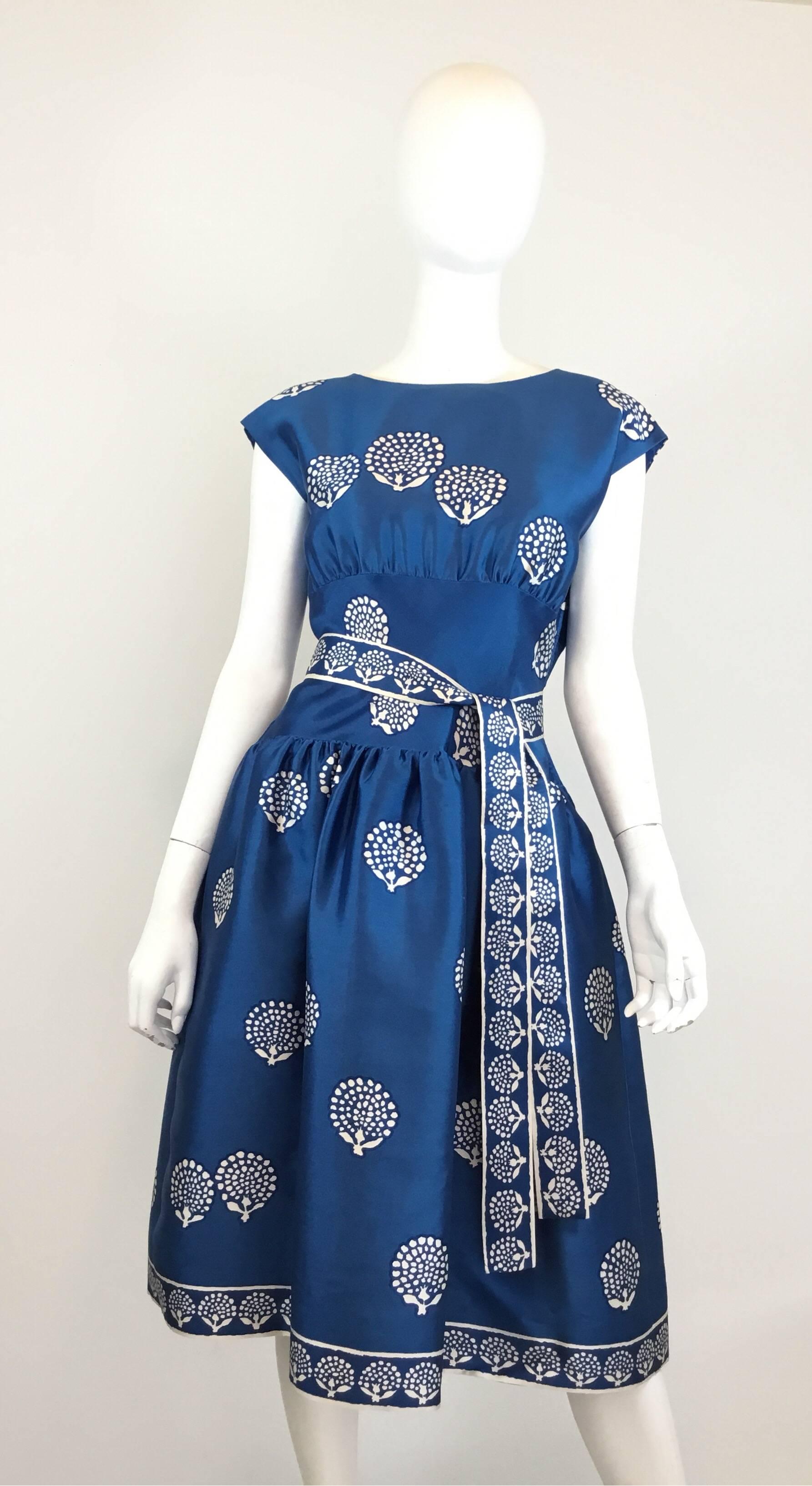 Normal Norell silk dress from the 1950's features a beautiful blue and white print throughout with zipper fastenings along both sides of the bodice,  back button closures, an additional waist tie fastening, pockets at the hips, and a full skirt.