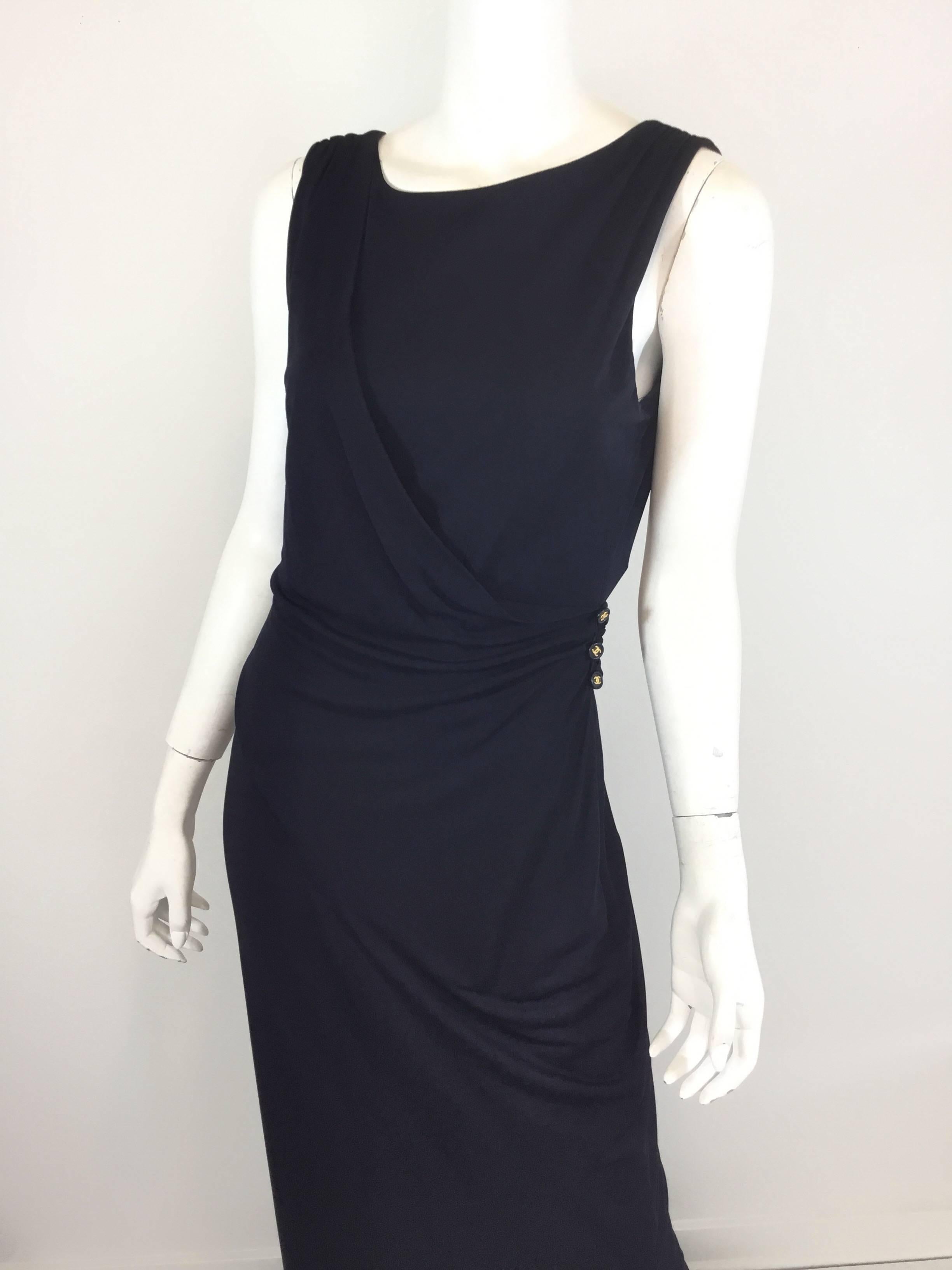 Chanel dark navy gown features signature CC buttons at the hip that attach the sash detail beginning at the right shoulder, plunging open back with a zipper fastening. Dress is fully lined. Labeled size 42, 100% rayon, made in France.

Measurements: