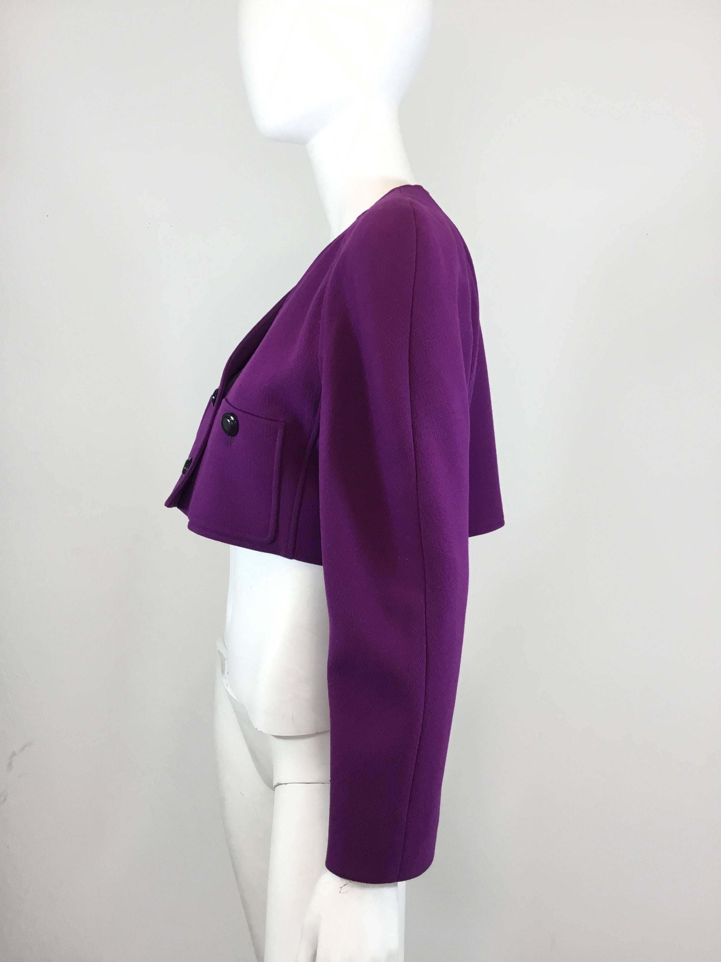 Valentino cropped jacket featured in purple wool crepe has two button closures along with two buttoned pockets at the bust. Jacket is labeled a size 8, and fully lined. Jacket has a small hole at the front of the left sleeve.

Measurements:
bust