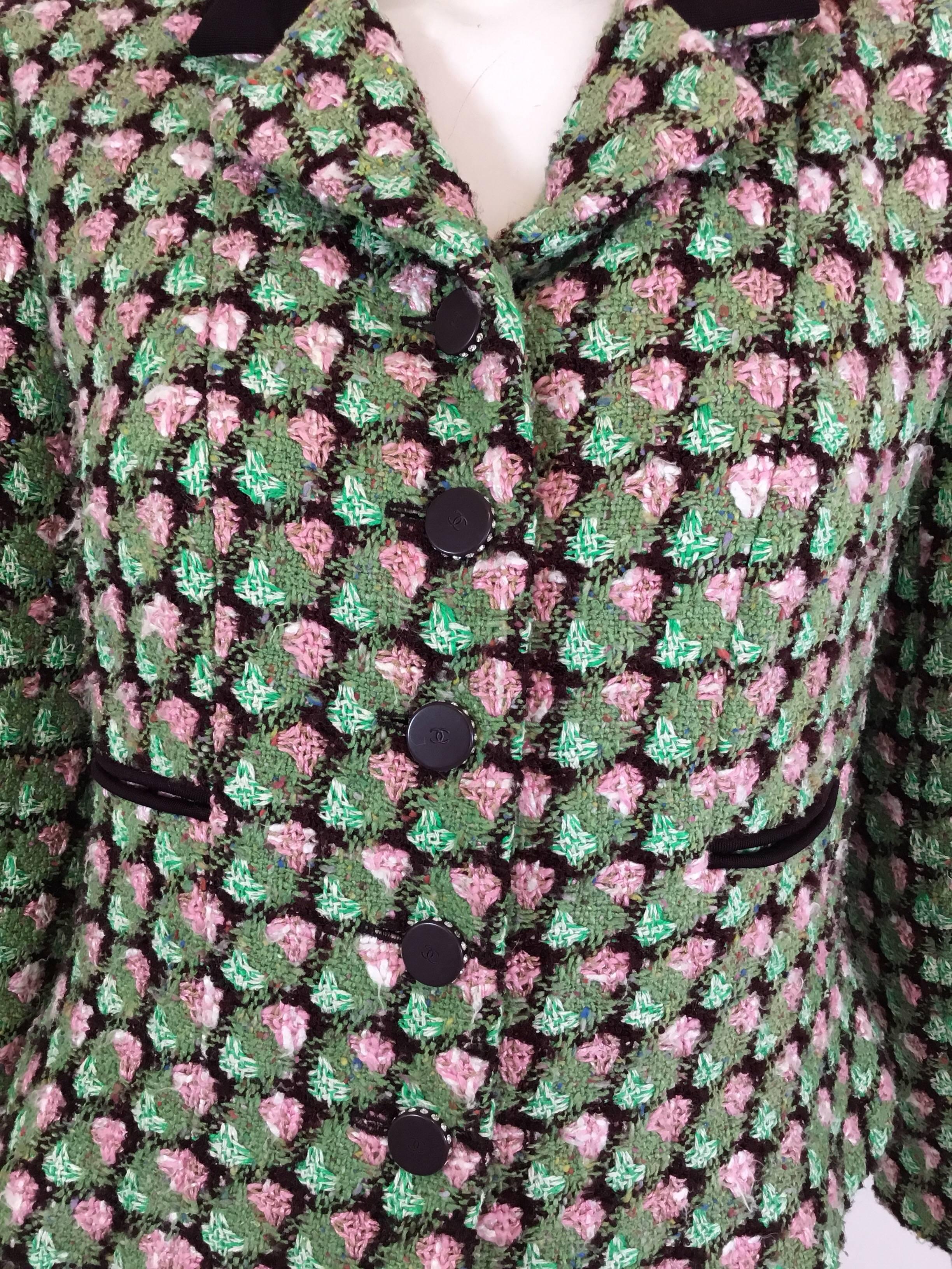 Chanel tweed jacket featured in green with an eggplant-colored collar, rhinestone encrusted button closures along the front and on the cuffs. Jacket has two uncut slip pockets at the waist and a full lining with a chain along the hem. Labeled size