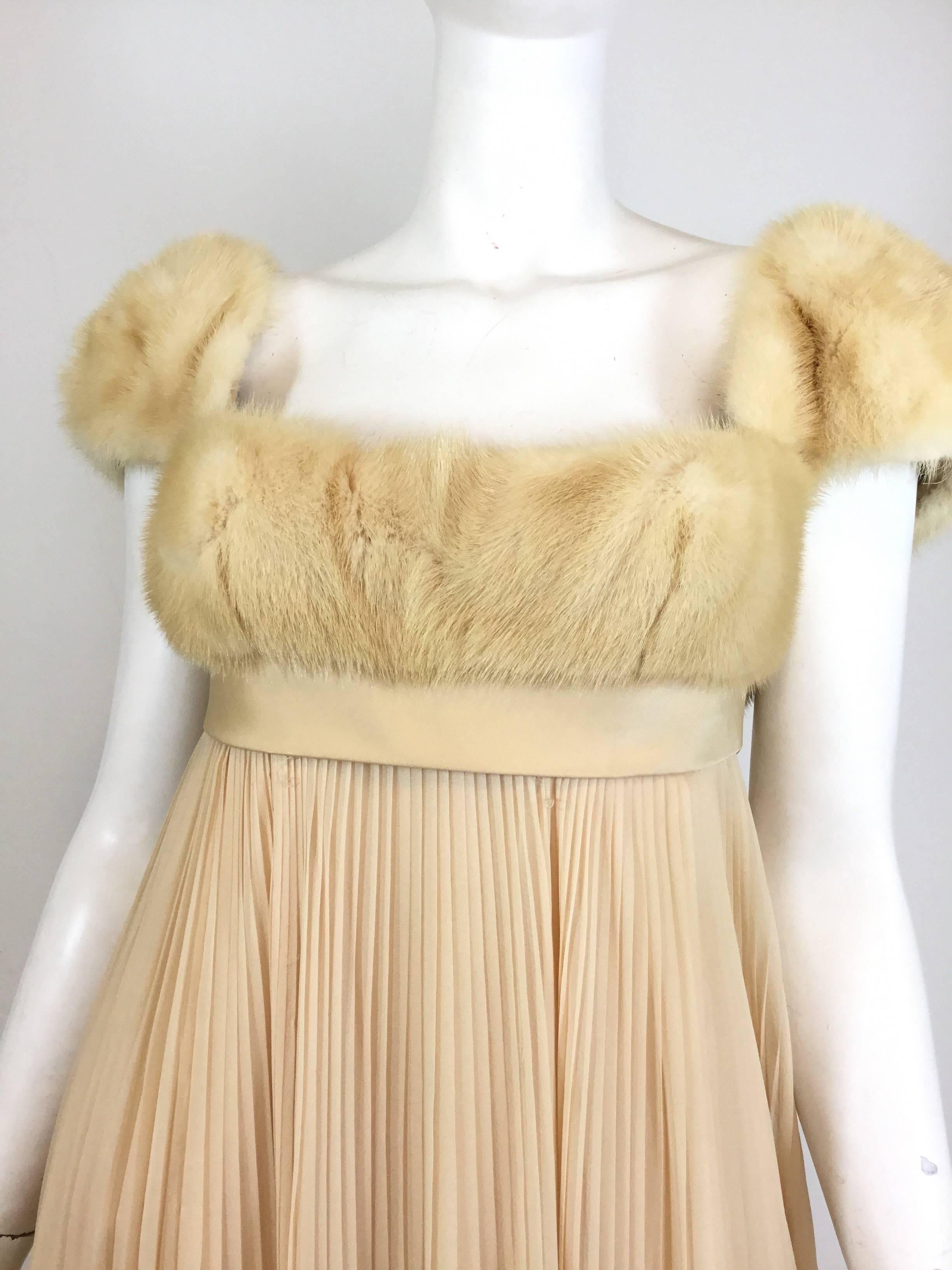 Gorgeous Sarmi gown featured in a cream/beige color with mink fur bust and sleeves. Skirt has a pleated silk chiffon design with a back zipper and hook-and-eye fastening. Gown is fully lined. There is some discoloration on the silk chiffon at the