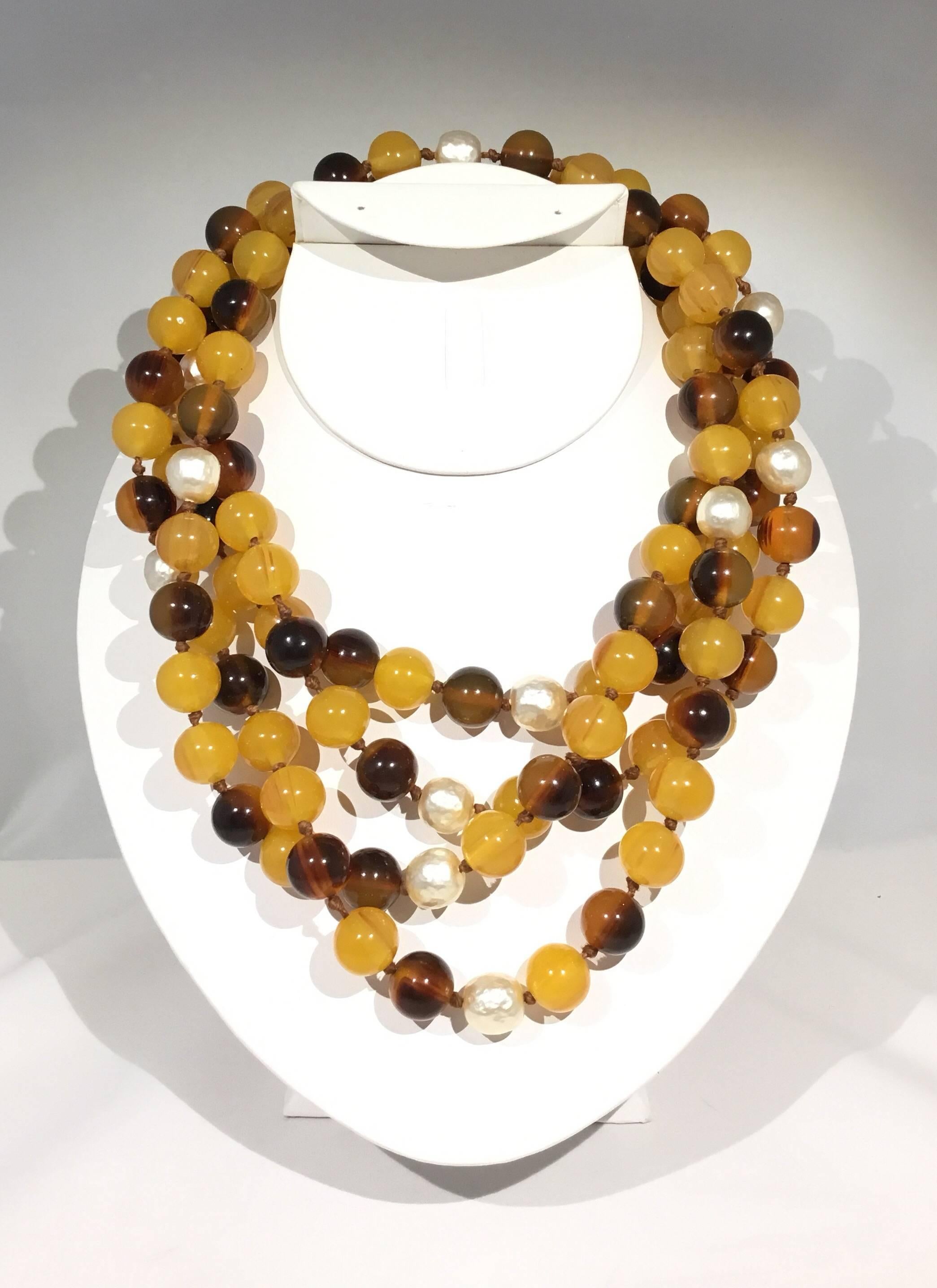 Bakelite and faux pearl necklace in variations of brown/tan on a knotted strand. Necklace has a clip clasp closure and is approximately 39 inches. Can be worn doubled or single strand.