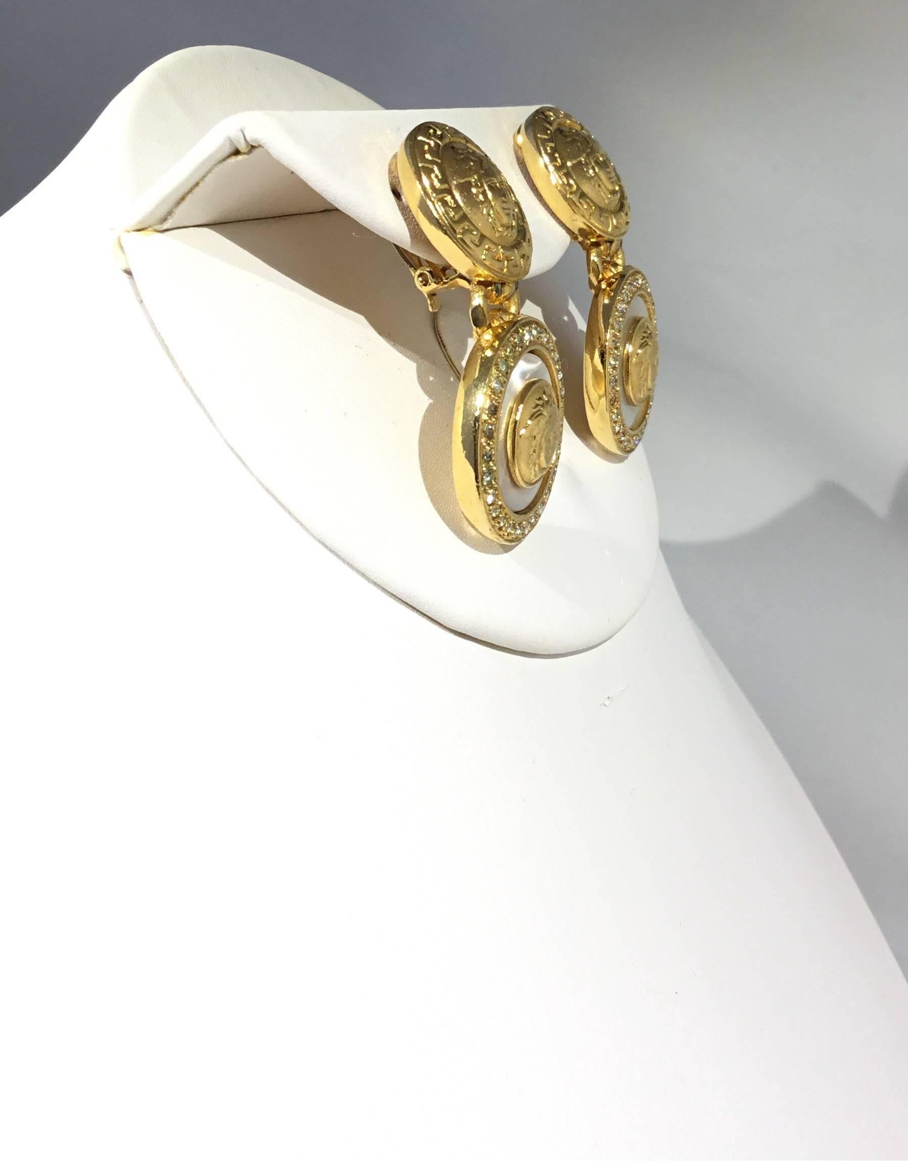 Gianni Versace gold tone clip on earrings featuring a signature Medusa design. Made in Italy, approximately 2 inches long.