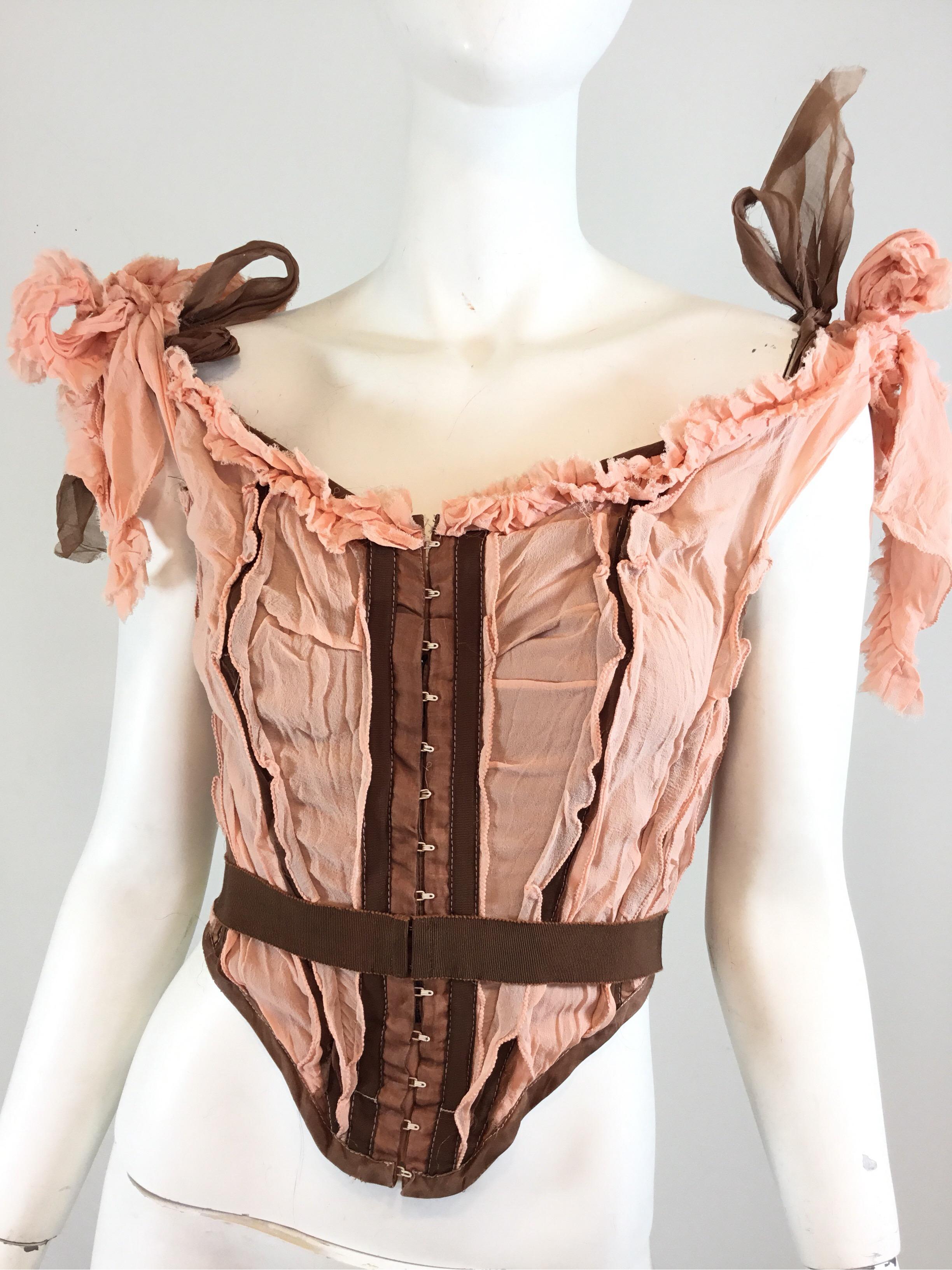 Jean Paul Gaultier corset from Spring/Summer 2005 RTW collection. Corset is featured in a pink and brown color with lace tie and hook closures. Shoulder straps are adjustable and can be untied. Designer label has been removed from the