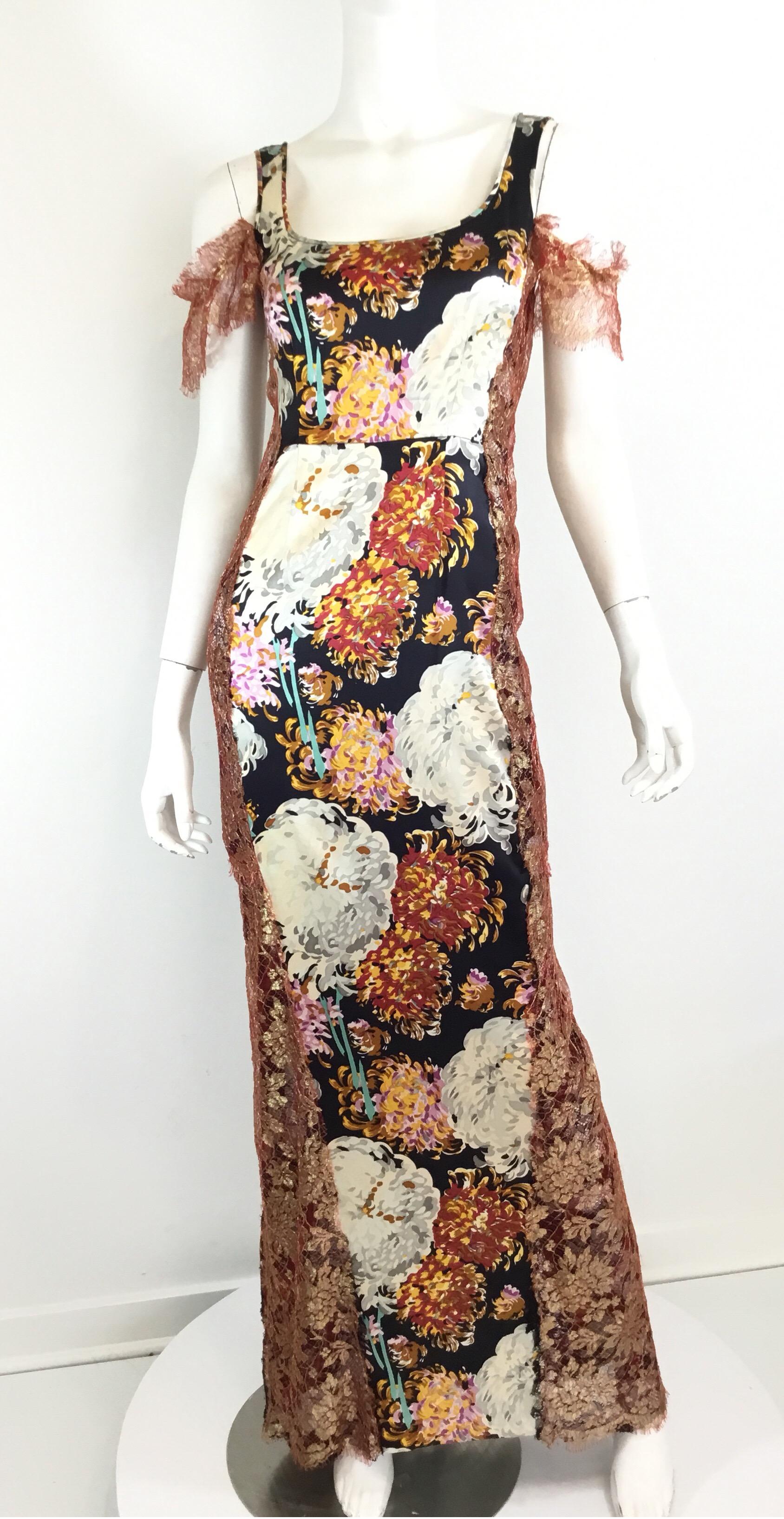 Beautiful Dolce & Gabbana Dress, circa 1990’s. Dress features a floral print on a silk-blend fabric with a cold-shoulder style, red and metallic gold lace sleeves and side panel. Black lace fishtail hem at the back and a back zipper fastening. Size